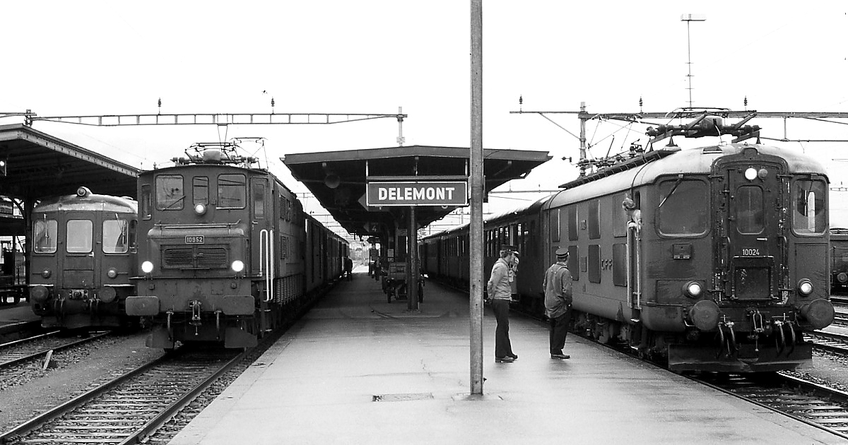 An einem völlig verregneten Julitag 1983 treffen sich die Ae 4/7 10952 und die Re 4/4 I 10024 im Bahnhof Delemont