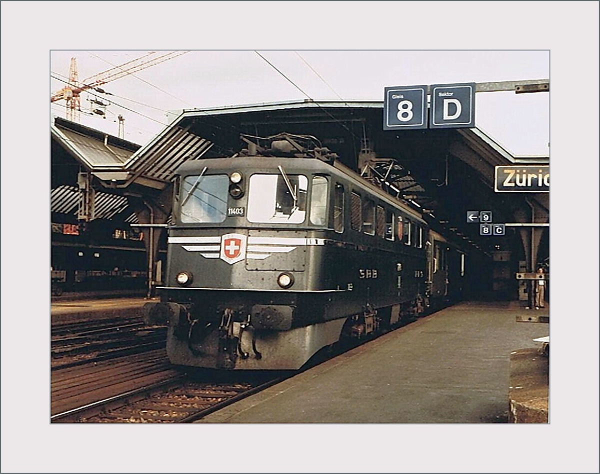 Die SBB Ae 6/6 11403  Schwyz  wartet in Zürich HB mit einem Regionalzug auf die Abfahrt. 
Die Ae 6/6 11403 war nach den beiden Prototypen Ae 6/6 11401 (Ticino) und 11402 (Uri) die erste Serien-Lok der 120 Maschinen umfassenden Baureihe Ae 6/6. 

Analogbild vom September 1984
