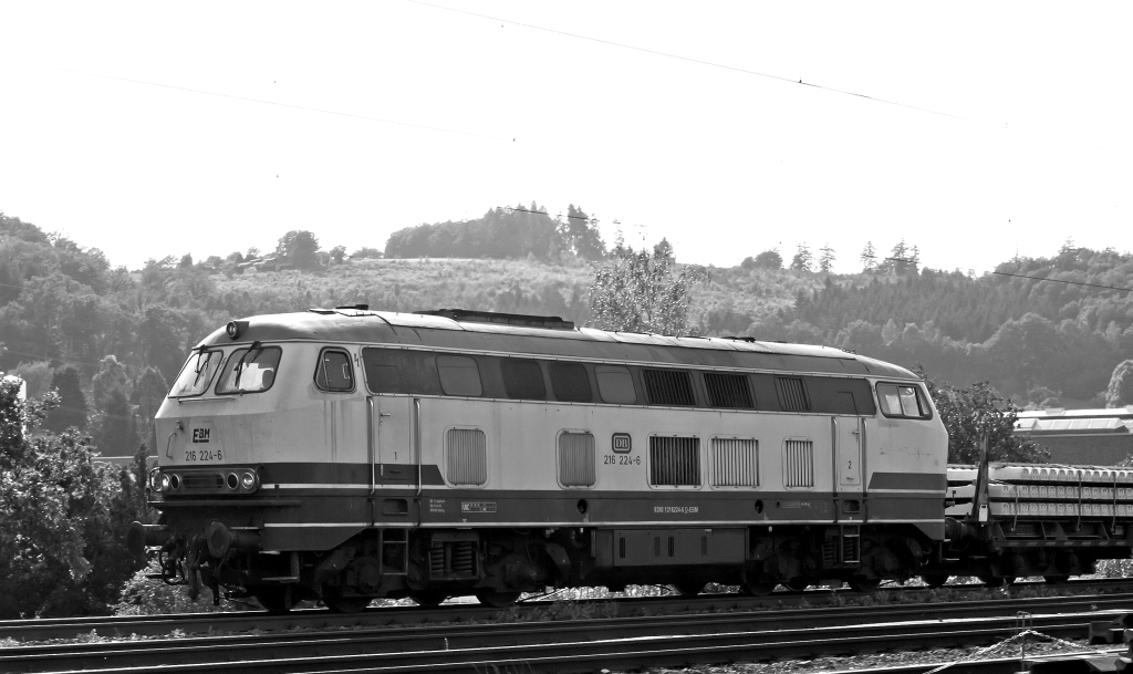 Die 216 224-6 der EBM Cargo (Gummersbach) kommt mit einem Schwellenzug am 29.07.2011  in Siegen (Kaan-Marienborn) und f�hrt Richtung Wilnsdorf-Rudersdorf . Die Lok wurde 1968 bei Krupp unter der Fabriknummer 4885 gebaut, es war die letzte der Serie.
Hier im Gegenlicht.