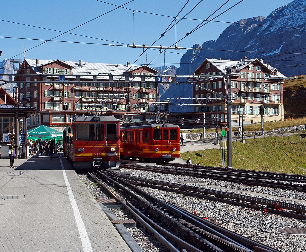 Vor der Kulisse des Hotel Bellevue des Alpes: Triebzug (2 gekuppelte BDhe 4/8) der Jungfraubahn vorne Triebwagen Nr. 214 hinten 211 verlsst am 02.10.2011 den Bf Kleine Scheidegg (2064 m. . M.), und fhrt hinauf zum Jungfraujoch. Rechts abgestellt Dhe 2/4 Triebwagen Nr. 209 mit Steuerwagen Bt 33.