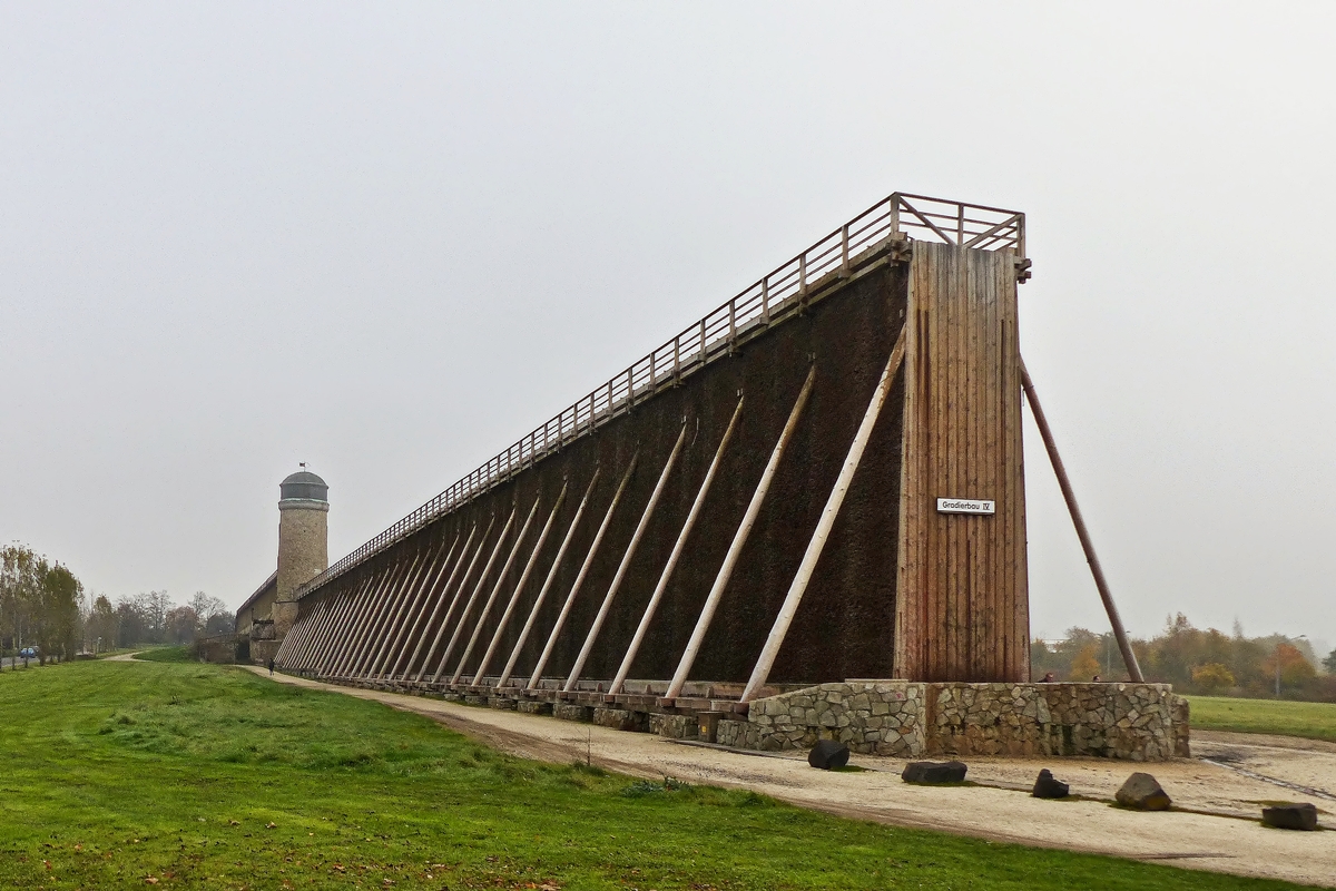 . Bad Nauheim (Wetterau) - Die Gradierbauten IV/V, die sogenannte Lange Wand mit dem Windmhlenturm. 01.11.2014 (Jeanny) 

Ein Gradierwerk ist eine Anlage zur Salzgewinnung. Sie besteht aus einem Holzgerst, das mit Reisigbndeln (vorwiegend Schwarzdorn) verfllt ist. Das Verb  gradieren  bedeutet  einen Stoff in einem Medium konzentrieren . Im Falle eines Gradierwerks wird der Salzgehalt im Wasser erhht, indem Sole durch das Reisig hindurchgeleitet wird, wobei auf natrliche Weise Wasser verdunstet. Auerdem lagern sich Verunreinigungen der Sole an den Dornen ab; dadurch wird die Qualitt des erzeugten Salzes erhht.