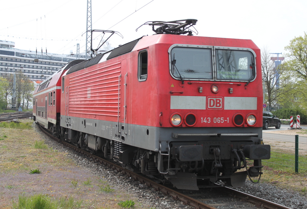 143 065-1 mit RE 18490 von Berlin Hbf(tief)nach Warnemünde bei der Einfahrt in Warnemünde im Hintergrund lag die 294 m lange MSC Magnifica.13.05.2017