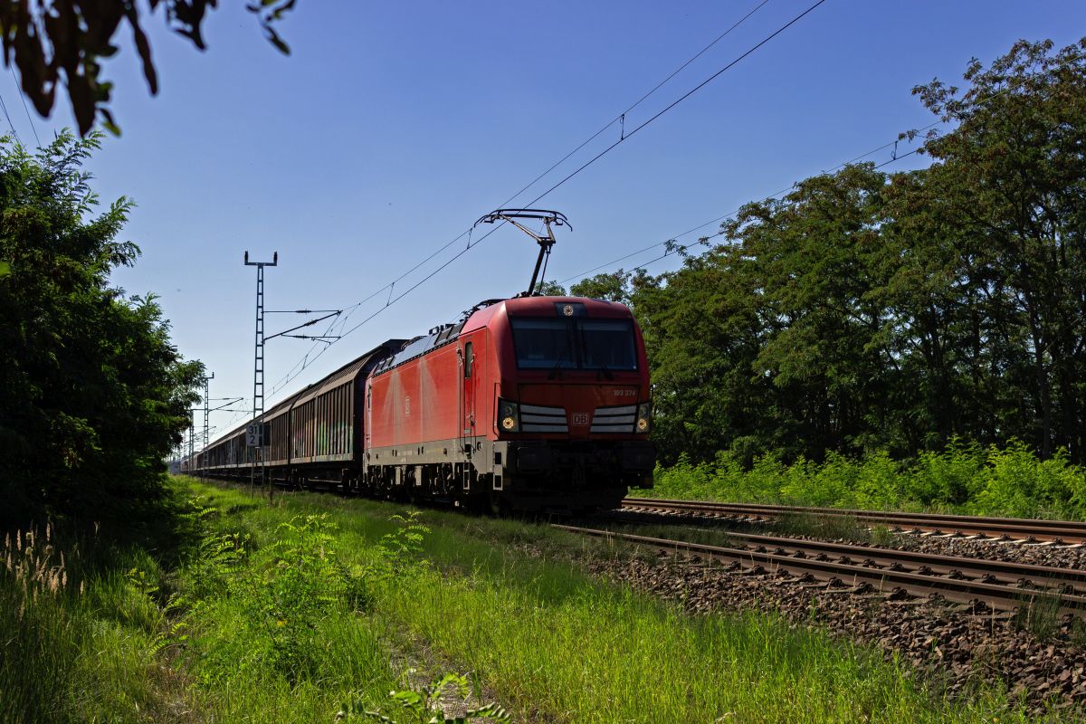 193 374 rollt am 06.09.23 mit einem G�terzug durch den nahe des Berliner Flughafens gelegenen Ort Wa�mannsdorf und wird in wenigen Minuten den alten Flughafenbahnhof Sch�nefeld durchfahren.
