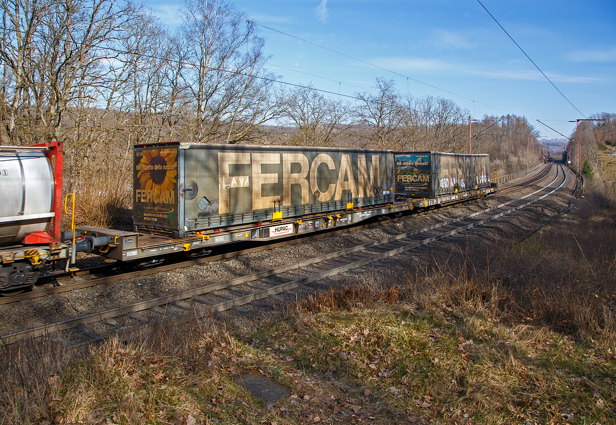Achtachsiger niedrig gelegte Doppelwagen Jumbo II / Mega II (Trag-/Taschenwagen-Doppeleinheit) der Gattung Sdggmrrss, 83 85 4933 297-9 CH-HUPAC, der Hupac Intermodal SA, am 13.03.2022 im Zugverband bei einer Zugdurchfahrt bei Wilnsdorf-Rudersdorf. Hier beladen links mit einer FERCAM Sattelzug-Wechselbrücke und rechts (hinten) mit einem FERCAM Sattelzugauflieger.

Diese Wageneinheiten bestehen aus einer niedrigen Tragwagenhälfte für Container und Wechselbehälter („CT“) und einer niedrigen Taschenwagenhälfte („SK“). Die beiden Wagenhälften sind mit einer, im Normalbetrieb nicht zu trennenden, (von den Waggons der RoLa, Saadkms 690, abgeleiteten) Kurzkupplung verbunden.

Der niedrig gelegte Doppelwagen Mega II ist fast 37 Meter lang. Er wurde 2003 eingeführt und ist heute auf allen Shuttle Net-Relationen der HUPAC im Einsatz. Der Mega-Wagen ermöglicht den Transport von Standard- und Megatrailern mit einer verfügbaren Innenhöhe von 2,55 bis 3,0 Metern je nach Streckenprofil. Durch die niedrig gelegte Ladefläche können C 70-400 kodifizierte Jumbo-Wechselbehälter bis Norditalien und High-Cube-Container bis Süditalien auf der Gotthardstrecke transportiert werden.

Zusätzlich der Eignung für die neuen Megatrailer, wegen deren Umschlagtechnik mittels tiefliegenden Greifkantenbeschlägen ein sehr niedrig aufbauender Wagenrahmen erforderlich ist, sollten auch Container und Wechselbehälter mit großen Höhenmassen alpenquerend befördert werden können. Damit war ein über die Ladelänge nicht in der Höhe gekröpfter Wagenrahmen erforderlich. Die verglichen mit der „Standardhöhe“ von 1.175 mm über Schienenoberkante (SOK), sehr niedrige Aufstandshöhe von nur 855 mm des MEGA II machte den Einsatz von Drehgestellen der Bauart Y31 Lsi(f) notwendig. Diese weisen eine geringere Bauhöhe, durch kleinere Radsätze mit 760 mm Laufkreisdurchmesser und maximal 18 t Radsatzlast, auf.

Hersteller dieser Wagen ist die Ferriere Cattaneo in Giubiasco (Schweiz), die 115 Wagen (230 Wagenmodule) hergestellt hat.
