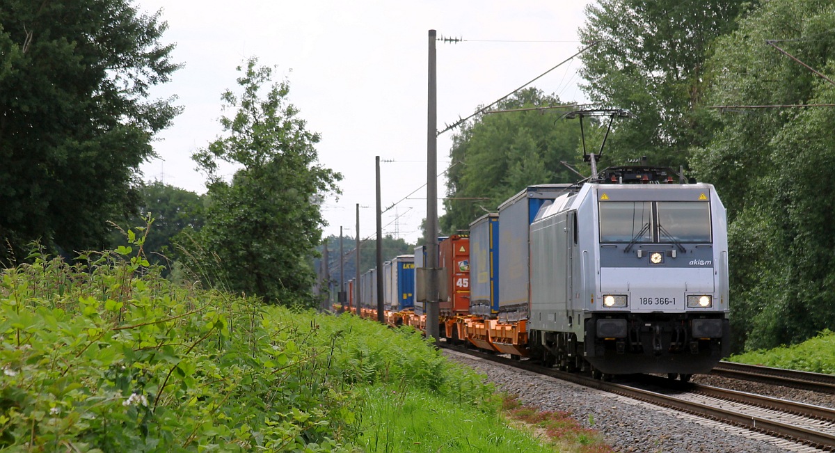 AKIEM 186 366-1 mit Tragwagenzug an einem Bü bei Lotte, 09.06.2024