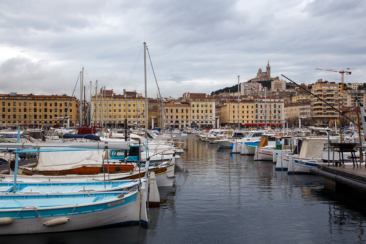 Alter Hafen von Marseille (le Vieux-Port de Marseille) am 25.03.2015 mit Blick (oben) auf die Wallfahrtkirche Notre-Dame de la Garde (im Volksmund La Bonne Mère – „die gute Mutter“). 

Der Hafen entstand in der Antike. Er ist das historische und kulturelle Zentrum von Marseille und war bis Mitte des 19. Jahrhunderts auch sein wirtschaftliches Zentrum für den Seehandel im Mittelmeer und für den Handel mit den französischen Kolonien. Das Hafengewerbe verlagerte sich dann allmählich nach Norden zum jetzigen Marseille Europort. Heute ist der Alte Hafen ein Yachthafen, ein beliebter Versammlungsort und das touristische Wahrzeichen der Stadt. Von ihm fahren aber auch die Fähren zu den Frioul Inseln (Chateau d' If und Port Frioul). Auch einige Fischerboote ankern noch hier, täglich findet am Morgen am Quai de la Fraternité ein Fischmarkt statt. 
