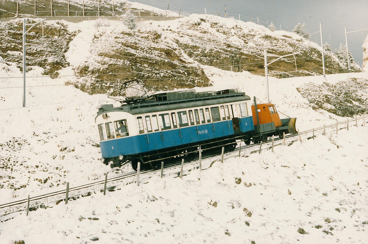 ARB: BDhe 2/3 6 (1911) noch im blauen Kleid mit Schneepflug zwischen Rigi Kulm und Rigi Staffel im November 1985. Fr das Fhrerhaus des Schneepfluges wurde die Kabine eines alten Mercedes Lieferwagen zweckentfremdet. Zu dieser Zeit befand sich der Triebwagen in einem sehr schlechten Zustand. Aus diesem Grunde war er nur noch selten auf der Strecke unterwegs. Auch eine Total-Revision war damals noch keine beschlossene Sache.
Foto: Walter Ruetsch 