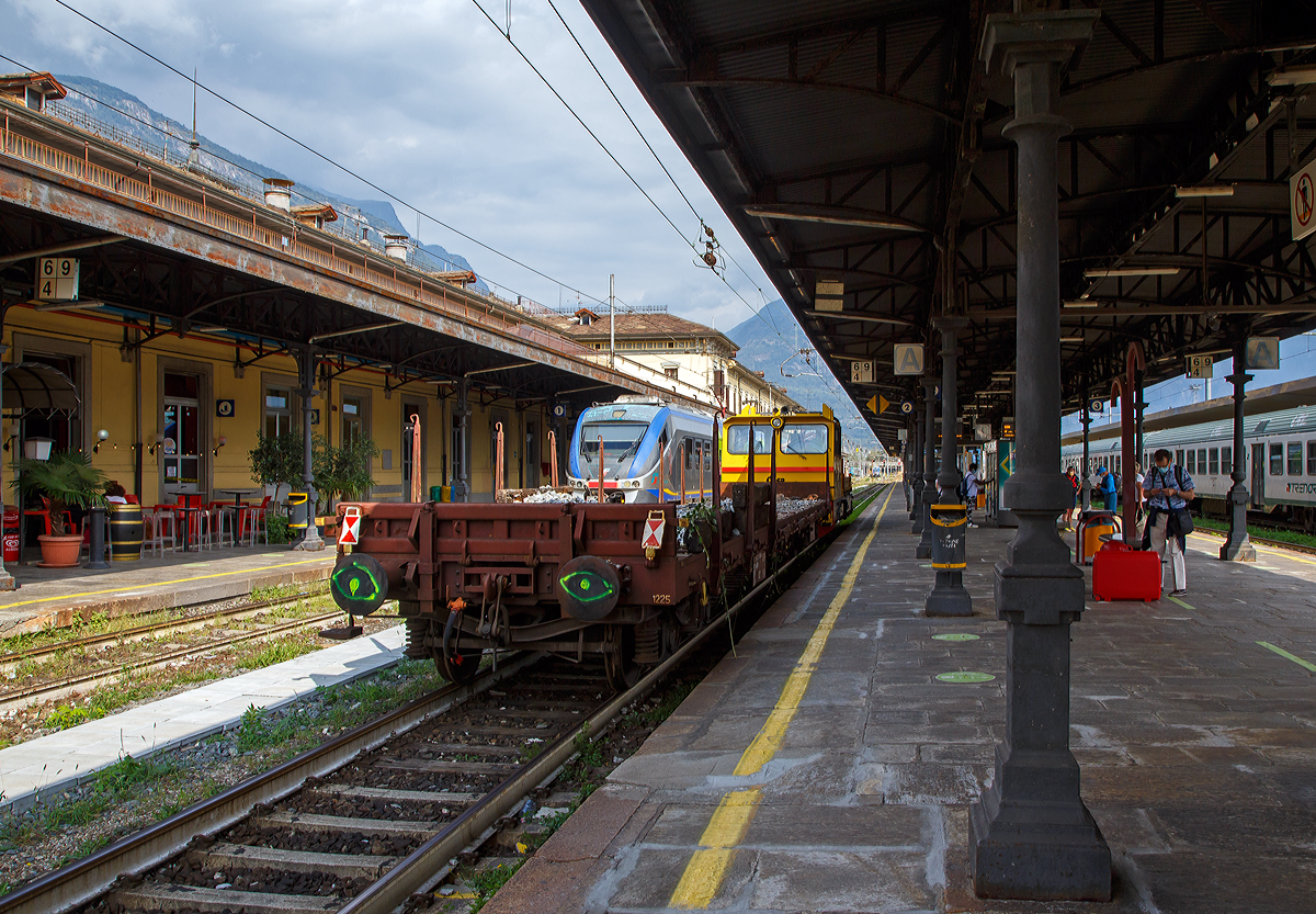 Das Italienische MerMec Gleisarbeitsfahrzeug IT-RFI 152 194-2 der RFI (Rete Ferroviaria Italiana) fährt am 08.09.2021 mit einem vierachsigen Flachwagen durch den Bahnhof Domodossola in Richtung Norden.