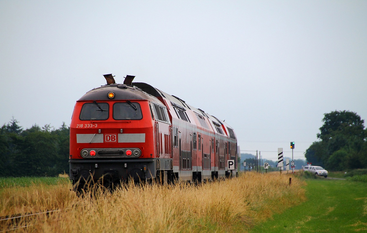 DB Regio Kiel 218 333-3 schiebt hier ihre RB nach Kiel durchs Flachland bei Jübek. Die Aufnahme entstand am Bü Sollbrück III. 27.06.2014