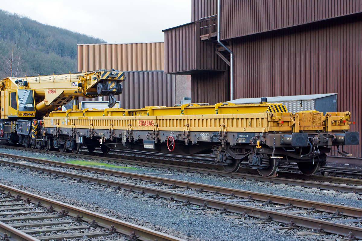 
Der Schutzwagen 99 80 9320 005-8 D-STRA der STRABAG RAIL GmbH, zum 150 t Kirow Gleis- und Weichenbaukran KRC 1200+ „DONAU“, abgestellt am 25.12.2014 am KSW Bahnhof Siegen-Eintracht (Betriebsbereich Eisern-Siegener Eisenbahn).

TECHNISCHE DATEN von dem Schutzwagen 99 80 9320 005-8 D-STRA:
Spurweite: 1.435 mm
Eigengewicht: 23.900 kg
Maximale Nutzlast: 56,1 t
Anzahl der Achsen: 4
Länge über Puffer: 19.900 mm
Länge der Ladefläche: 18.500 mm
Drehzapfenabstand: 15.000 mm
Achsabstand im Drehgestell: 1.800 mm
Bremse: OGP – DRV - 600
Höchstgeschwindigkeit: 100 km/h 
Zugelassen für Streckenklasse: CE oder höher
Kleinster befahrbarer Gleisbogen: R = 75m
Baujahr: 2009