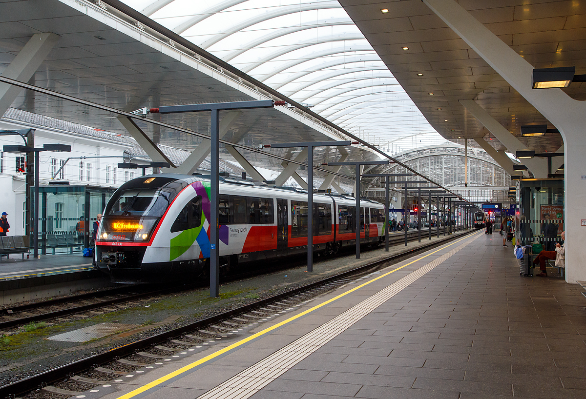 Der zweiteilige Siemens Desiro Classic (Dieseltriebzug) ÖBB 642 136 / 642 636 (95 80 0642 136-5 D-DB / 95 80 0642 636-4 D-DB), steht am 11.09.2022 im Hbf Salzburg, als ÖBB (Salzburg Verkehr) RX 21 Braunau am Inn nach Freilassing, zur Abfahrt bereit. 

Der Desiro Classic wurde 2001 von Siemens in Uerdingen (ex DUEWAG) gebaut, der VT 642 136 unter der Fabriknummer 92018 und der VT 642 636 unter der Fabriknummer 92168.

Seit dem Fahrplanwechsel im Dezember 2019 haben die ÖBB sechs Dieseltriebwagen der BR 642 (642 083, 084, 087, 130, 136 und 204) von der DB Regio Netz Verkehrs GmbH angemietet, diese entsprechen weitgehend der ÖBB Baureihe 5022. Die Triebzüge sind nun in Salzburg beheimatet, sind aber noch in Deutschland registriert und tragen die deutschen NVR-Nummer. Die Wartung erfolgt durch die ÖBB in Salzburg. Die Fahrzeuge werden auf der Mattigtalbahn (Braunau–Salzburg) mit Durchbindung nach Freilassing eingesetzt. 

Hinten sieht man die Integration der denkmalgeschützten Bahnsteigüberdachung in den modernen Glasbau. Man beachte die Stromschiene (Deckenstromschienen DSS System Furrer+Frey) als Oberleitung an den Gleisen 3 und 4. Mit der Erneuerung des schönen Gewölbes über den Gleisen 3 und 4 musste auch die Fahrleitung neu gestaltet werden. Die Architekten haben sich für die Deckenstromschiene entschieden, mit entscheiden war wohl auch die geringere Durchfahrtshöhe unter der denkmalgeschützten Bahnsteigüberdachung. Aber ich finde es sieht wirklich gut aus.

Deckenstromschienen DSS System wurde 1984 von der Schweizer Furrer+Frey AG entwickelt. Seit 1984 liegen auch störungsfreie Betriebserfahrungen vor. Die höchste Betriebsgeschwindigkeit im Tunnel liegt bei 250 km/h, in Versuchen wurden 302 km/h erreicht, aber solche Geschwindigkeit werden im Hbf nicht gefahren.
