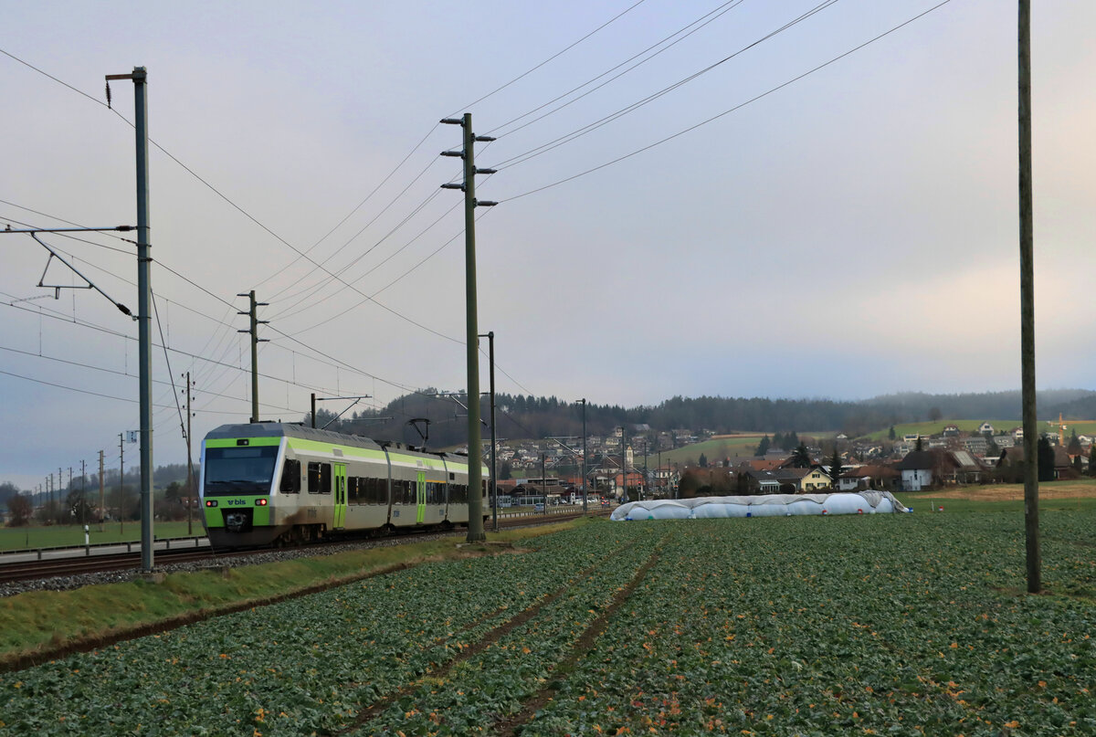 Die ehemalige VHB (Vereinigte Huttwil-Bahnen) / Strecke der ursprünglichen LHB(Langenthal-Huttwil-Bahn) / heute BLS S-Bahn Luzern S6 und S7: Von Lindenholz her gesehen fährt BLS NINA 525 006 Richtung Langanthal; Blick auf Madiswil mit seiner markanten Kirche. 31.Dezember 2021 