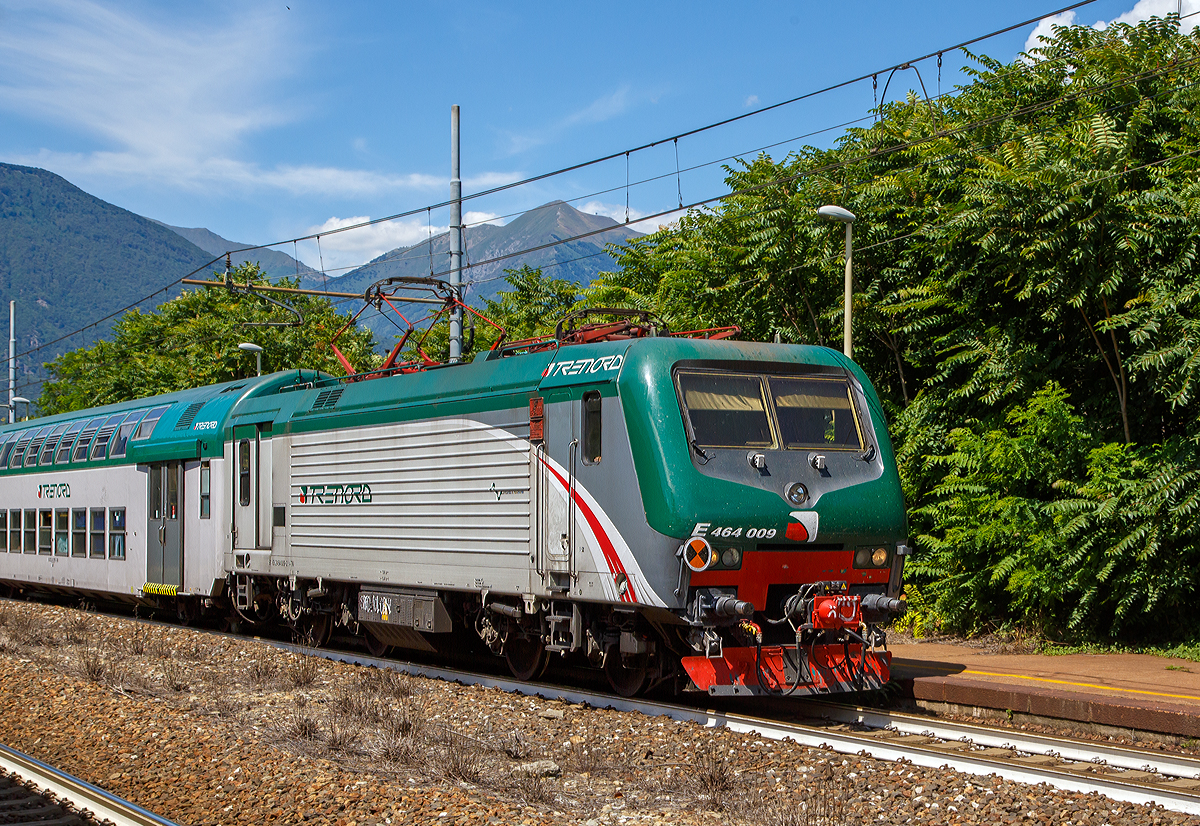 
Die rechtsaubere Trenord E.464.009 (91 83 2464 009-2 I-TN), eine Bombardier TRAXX P160 DCP, fährt am 03.08.2019 mit einem RE (Domodossola nach Milano) durch den Bahnhof Vogogna (Stazione Ferroviaria di Vogogna Ossola).