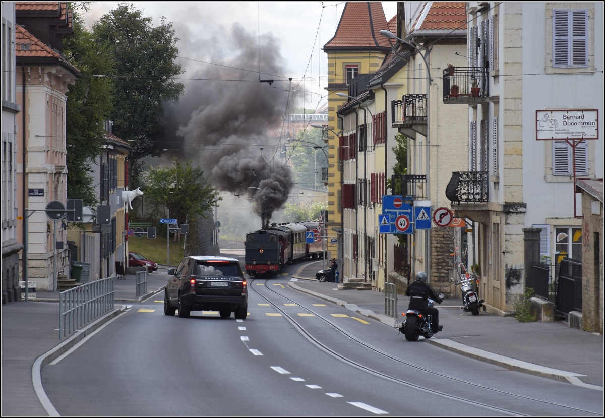 Eine etwas ungewöhnliche Verkehrsteilnehmerin in La Chaux-de-Fonds. 

Um die Kurve gefahren und schon rette sich, wer kann. Denn CP E 164, heute bei La Traction, schnaubt mit viel Rauch als Geisterfahrerin die Rue du Manège hinauf. September 2021.