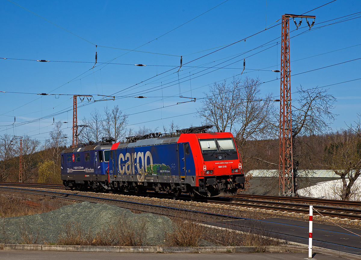 Ja, „Grezi“ oder „Servus“.....
Die SBB Cargo Re 421 371-6 (91 85 4421 371-6 CH-SBBC), ex Re 4/4 II 11371, mit Werbung Zrich – Mnchen 6 x tglich in 3,5 Stunden, fhrt am 30.03.2021 mit der SBB Cargo Re 484 016-1(91 85 4484 016-1 CH-SBBC), ex E 484.016 SR, einer TRAXX F140 MS am Haken durch Rudersdorf (Kr. Siegen), an der Dillstrecke (KBS 445), in Richtung Siegen.

Eine SBB Cargo Re 484 wie die 016-1 kann man eigentlich Deutschland nur mit viel Glck sehen, denn sie haben nur die Zulassungen fr die Schweiz und Italien. Sie haben keinen Stromabnehmer mit breiterer Wippe gem deutscher Vorschrift, auch die die deutsche Zugsicherung Indusi fehlt ihnen. Der Lz war auf dem weg nach Krefeld.

Lebenslufe:
Die Re 421 371-6 wurde 1983 von der SLM Winterthur (Elektrik BBC/ SAAS) unter der Fabriknummer 5235 gebaut und als Re 4/4 II 11371 an die SBB geliefert. Im Jahr 2002 erfolgte der Umbau zur Re 421 fr die SBB Cargo (Einsatz auch in Deutschland). Die zugelassene Hchstgeschwindigkeit fr die Schweiz betrgt 140 km/h und fr Deutschland 120 km/h.

Die Re 484 016-1 eine Bombardier TRAXX F140 MS wurde 2004 von Bombardier in Kassel unter der Fabriknummer 34009 gebaut und an die SBB Cargo AG, als E 484.016 SR geliefert. 