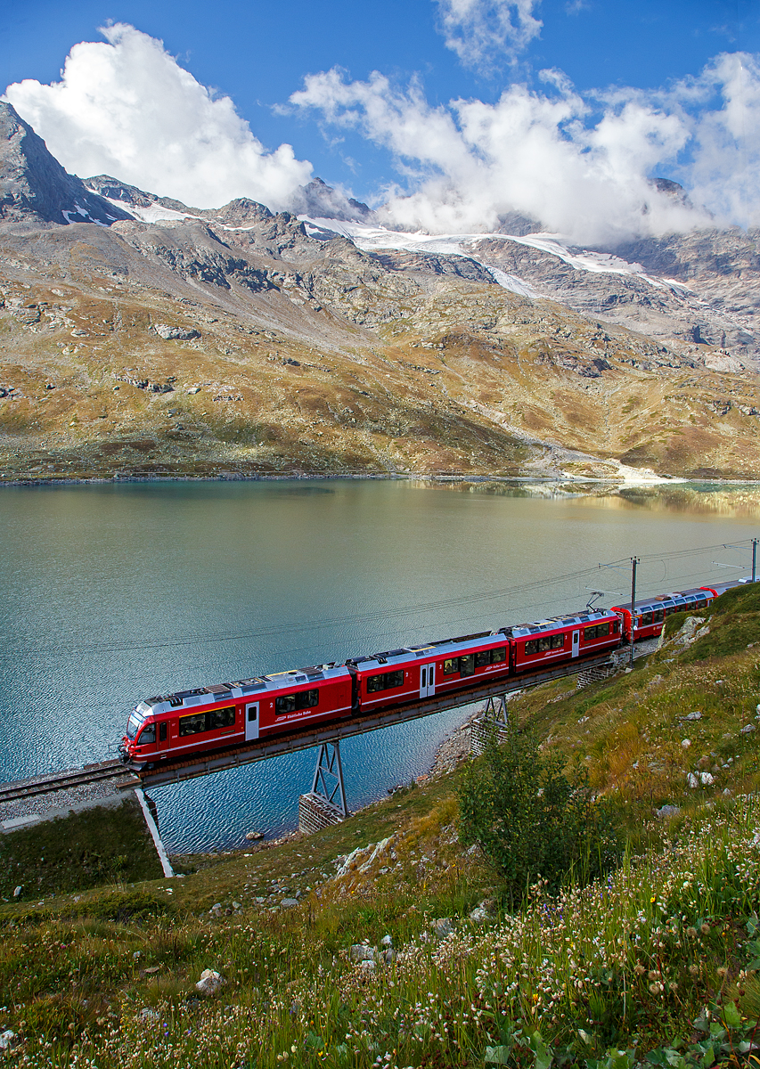 Leider unter einer leidigen Fotowolke....
Der RhB ALLEGRA-Zweispannungstriebzug (RhB ABe 8/12) 3504  Dario Cologna  fährt am 06.09.2021, mit dem Bernina Express nach Tirano, bei Ospizio Bernina über die 46 m lange „Am See Brücke“ am Lago Bianco entlang. 

Hier oben beim Berninapass bzw. an der Staumauer des Lago Bianco befindet sich auch zugleich die Wasserscheide zwischen Donau und Po. In Richtung Tirano fließ das Wasser in den Po und somit ins Mittelmeer, in Richtung St.Moritz fließ das Wasser in die Donau und somit ins Schwarze Meer.
