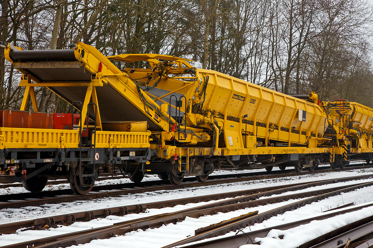 Plasser & Theurer Material-, Förder- und Siloeinheiten MFS 38 (teilweise BSW 2000 - Bunker-Schüttgut-Wagen genannt) der HERING Bahnbau, Burbach, Nr. 3, Schweres Nebenfahrzeug Nr. D-HGUI 99 80 9552 121-2, ex 97 19 22 550 17-5, ist am 11.12.2021 auf dem Betriebshof der Westerwaldbahn (WEBA) auf der Bindweide bei Steinebach/Sieg abgestellt.

Diese MFS 38 wurde 1993 von Plasser & Theurer gebaut, wobei als Fahrgestell ein vierachsiger ehemaliger Drehgestell-Flachwagen der Gattung Rs 680 (ex SSlmas 53), der 1962 von M.A.N. im Werk Nürnberg unter der Fabriknummer 146868 gebaut wurde, Verwendung fand. Diese Wagen wurden Plasser & Theurer vom Kunden beigestellt. 

TECHNISCHE DATEN:
Maschinenart: Material-Förder-Siloeinheit MSF 38
Hersteller: Plasser & Theurer
Spurweite: 1.435 mm (Normalspur)
Anzahl der Achsen: 4 (in 2 Drehgestellen)
Länge über Puffer:19.900 mm
Gesamtlänge mit Übergabeband: 23.550 mm
Drehzapfenabstand: 13.000 mm
Achsabstand im Drehgestell: 2.000 mm
Laufraddurchmesser: 1.000 mm (neu)
Drehgestell-Bauart: Minden Dorstfeld-Drehgestell 931 / 932
Breite: 2.890 mm
Höhe: 4.280 mm
Eigengewicht: 38 t
Max. Zuladung (Nutzlast): 42 t
Ladevolumen: 38 m³
Höchstgeschwindigkeit: 100 km/h (geschleppt)
Kleister befahrbarer Gleisbogen: R=120 m (angeschrieben)
Bremse: KE – GP
Motor: luftgekühlter Deutz Dieselmotor vom Typ F6L 912 F
Leistung: 82 kW
Dieseltankvolumen: 750 l
Übergabeband: +/- 45 Grad schwenkbar.
Entladezeit: 3,5 Minuten
Entladeabstand von Gleismitte: max. 4,5 m
Die Förderbänder sind in folgenden Geschwindigkeiten regelbar:
Siloband: 1. Gang (Speichern)   0 - 0,028 m/s / 2. Gang (Durchfördern)  0 - 0,140 m/s
Übergabeband: 0 - 1,000 m/s

Einsatz und Arbeitsweise:
Bei diesem MFS 38 (ohne nachfolgendes „D“) ist das Übergabeband beidseitig zum Gleis um 45 Grad schwenkbar, so ist ein  Entladen nebens Gleis oder zum Nachbargleis möglich. Die MSF 38 haben ein Fassungsvermögen 38 m³ bzw. eine Nutzlast von 42t, bei einem Eigengewicht von 38t. Die Förderbänder werden hydraulisch angetrieben. Der Antrieb des Hydraulikaggregates erfolgt durch einen luftgekühlten Deutz Dieselmotor vom Typ F6L 912 mit einer Leistung von 82 kW.

Mit den Materialförder- und Siloeinheiten können unterschiedliche Schüttgüter wie beispielsweise Abraum, Planum- und Frostschutzmittel oder Bettungsstoffe unkompliziert, geladen, gefördert, gespeichert und entladen werden. Das Abraumverladesystem ist weitestgehend automatisiert und benötigt zur Bedienung nur wenig Personal. Das System verfügt zudem über eine autarke Energieversorgung (durch Dieselmotore). Ein unabhängiges Entladen ist durch schwenkbare Übergabebänder an jeder geeigneten Stelle möglich. Die MFS-Wagen können in Kombination mit einer Beladestation in beliebiger Anzahl aufgereiht und vor Kopf be- und entladen werden.

Am Boden jedes MFS 38 befindet sich ein über die ganze Wagenbreite gehender Fördergurt und an der Stirnseite ein breites Abgabeförderband. Das Aushubmaterial fällt von der Maschine kommend auf den Bodengurt, wird zum Abgabeförderband gebracht und an die nächste Einheit übergeben. Dieser Vorgang wiederholt sich, bis die am weitesten entfernte Siloeinheit erreicht wird. Bei dieser hintersten Siloeinheit ist das Abgabeförderband an der Stirnseite des Wagens in Ruhestellung. Auch der Fördergurt am Boden des Wagens ist so lange in Ruhestellung, bis die obere Füllgrenze erreicht ist. Dann wird der Fördergurt in Bewegung versetzt und dadurch im Übergabebereich freier Raum für die weitere Beladung geschaffen. Durch die dem Fülltempo angepasste Geschwindigkeit des Fördergurts wird die ganze Siloeinheit vollständig gefüllt. Das Fassungsvermögen einer Siloeinheit beträgt 38 Kubikmeter.

Nach Füllung einer Teilgruppe des Abraumzuges kann diese von der Restgruppe abgekuppelt werden, zu einer Entladestelle gefahren und dort entleert werden, während die Restgruppe des Abraumzuges noch befüllt wird. Das Entladeband ist nach beiden Seiten ausschwenkbar. Die Entladung kann dabei auf einer Deponie erfolgen oder es können LKW's oder Waggons am Nachbargleis beladen werden. Die MFS 38 (ohne nachfolgendes „D“) des Abraumzuges können durch Ausschwenken aller Abgabeförderbänder gleichzeitig entleert werden. Die Entladung eines Wagens dauert ungefähr 3,5 Minuten.
