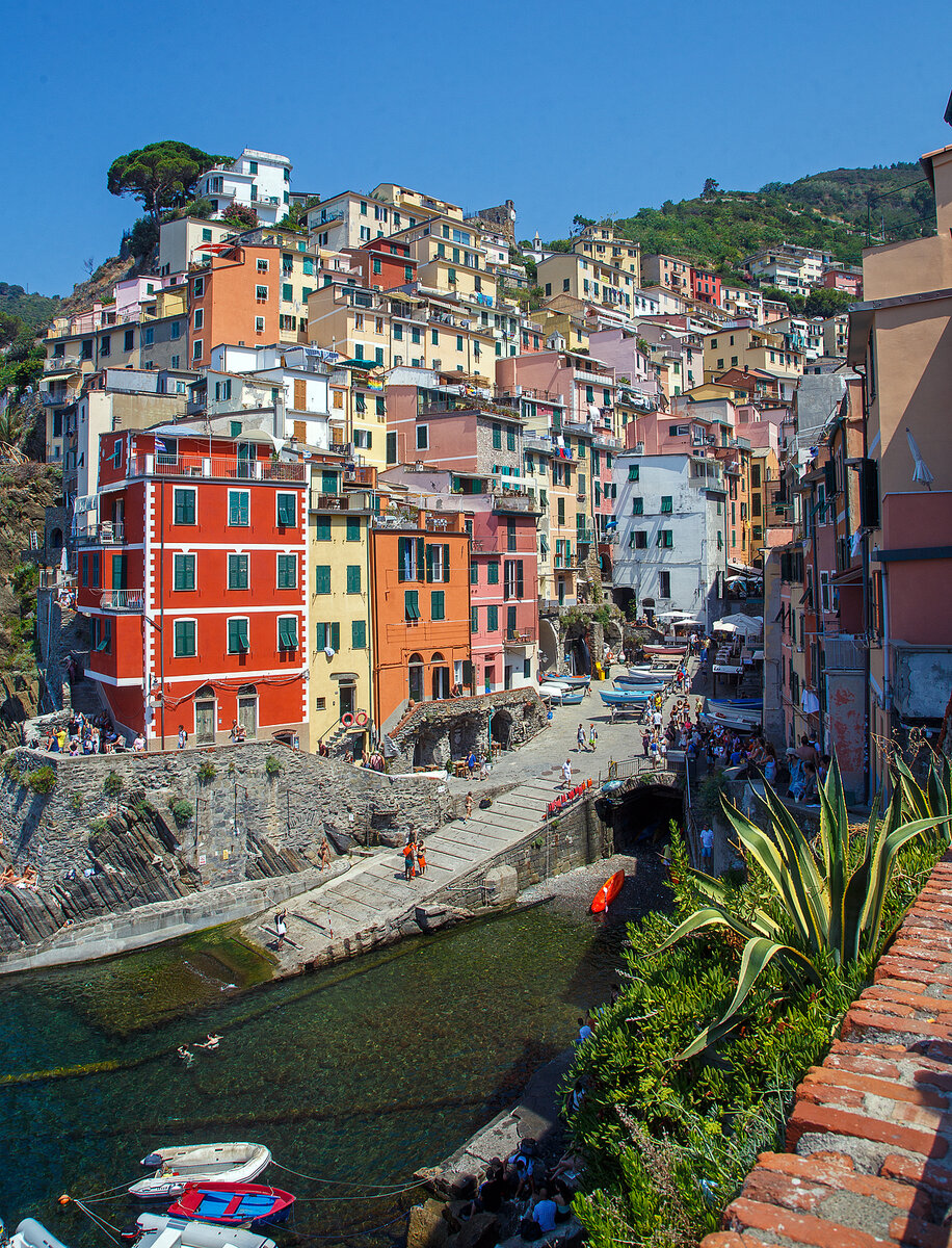 Riomaggiore (Cinque Terre) am 21.07.2022, hier der Blick auf die Bucht und das Zentrum mit den sich gegeneinander auftrmenden bunten Hausfassaden in allen mglichen Farbtnen.