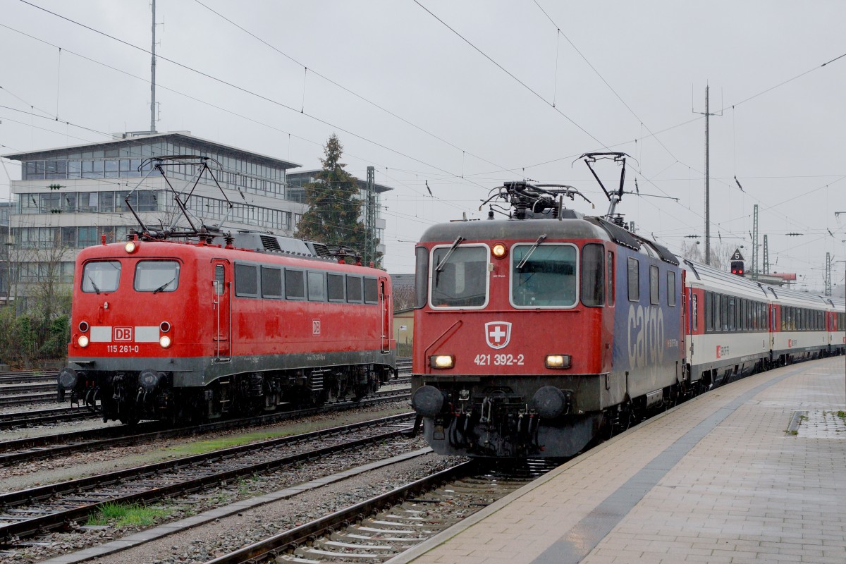 SBB/DB: Fotografieren in Singen am 20. November 2015 trotz starkem Wind und Dauerregen. Eher seltene Begegnung zwischen der 115 261-0 und der Re 421 392-2 von SBB CARGO im IC-Verkehr in Singen.
Foto: Walter Ruetsch 