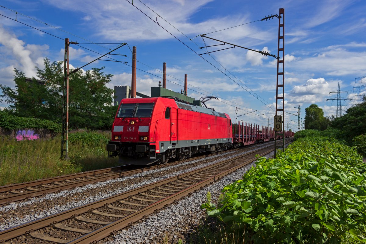 Vor der Kulisse der Kokerei Prosper in Bottrop f�hrt 185 352 am 18.08.2020 an der Spitze eines mit Stahlbarren beladenen G�terzuges entlang.