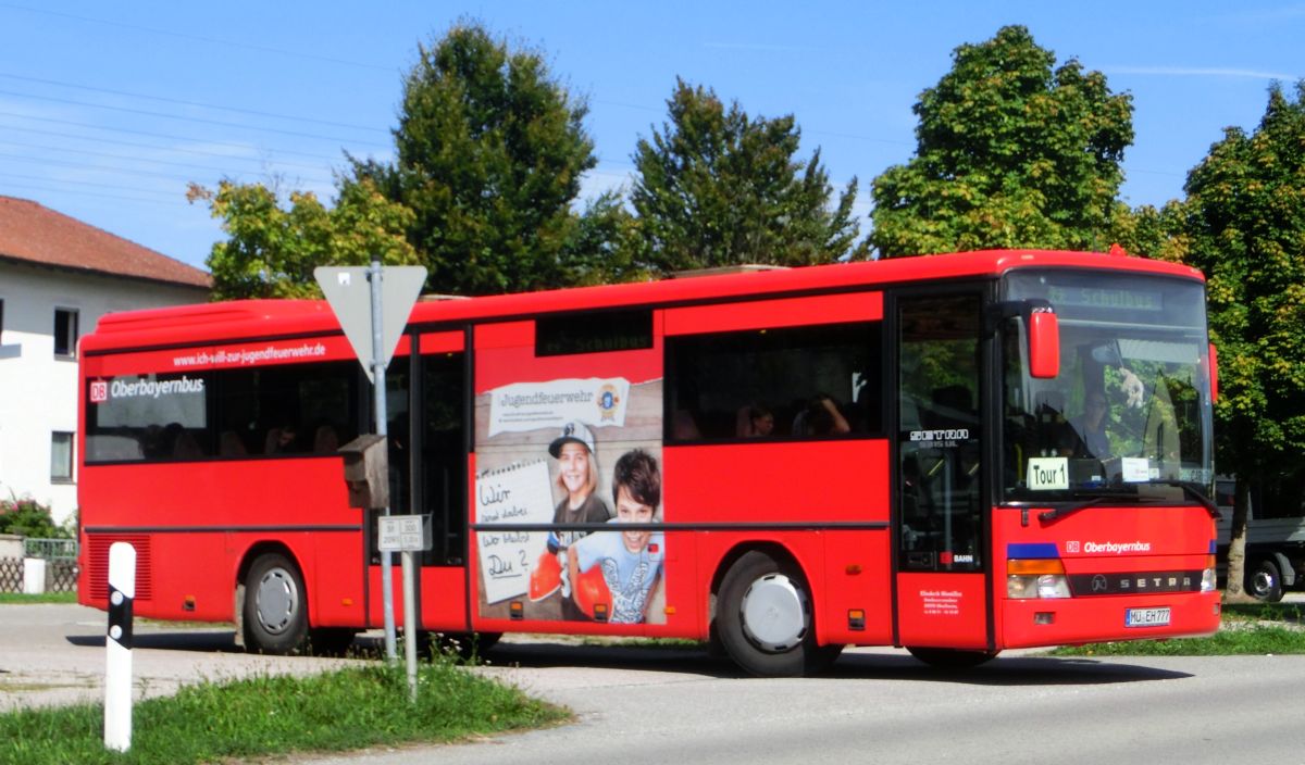 Wie mehrere Busse seiner Flotte hat Hinmüller Reisen aus Oberflossing bei Polling diesen Setra S 315 UL im Design der RVO / DB Oberbayernbus gestaltet und mit einer Werbefolie der Jugendfeuerwehr versehen. Dieses Exemplar ist bei Setra im Jahr 2000 vom Band gelaufen und hat 55 Fahrgastsitzplätze (mit kippbarer Sitzbank am Mitteleinstieg; Setra-Überlandbestuhlung Modell Special-Class mit Sicherheitsgurten) plus 2 Reiseleitersitze. Vorne, rechts und hinten ist jeweils eine LAWO-Matrix eingebaut. Der Antriebsstrang besteht aus dem Reihensechszylinder Typ MB OM 447 hLA mit 184 kW (250 PS) und dem Sechsgang-Handschaltgetriebe ZF S 6-85.
Abgelichtet wurde der Bus am Mittag des 17. 9. 2015 an der Wendeschleife vor der Inn-Apotheke in Kraiburg/Inn, als er aus Waldkraiburg kommend auf der RBO-Linie 6224 Kurs 034 unterwegs war.
