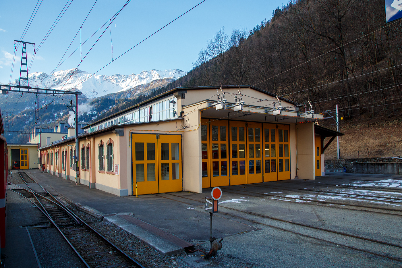 Der Lokschuppen, Depot und Werkstätte der Rhätischen Bahn / Ferrovia retica (RhB) in Poschiavo am 20 Februar 2017.

Der Bahnhof Poschiavo wurde auf Wunsch der Gemeinde etwas außerhalb des Ortes errichtet. Für die 1908 eröffnete Berninabahn bedeutet Poschiavo den wichtigsten Bahnhof südlich des Passes.Er besitzt eine Betriebswerkstätte, in der auch einige historische Fahrzeuge der Berninabahn stationiert sind. Im Depot mit angegliederter Werkstätte werden die Gleichstrom-Triebfahrzeuge der Rhätischen Bahn gewartet. Der Stützpunkt des Bahndienstes mit Fahrleitungsdienst betreut die gesamte etwa 60 km lange Bahnlinie. Im Jahre 1962 wurde das Stationsgebäude neu erbaut, von 1969 bis 1972 das Depot erweitert. 