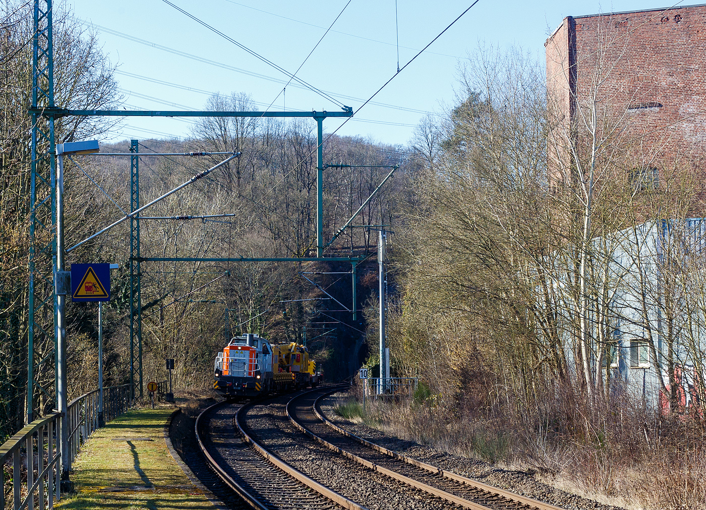 Die an die BEG - Bocholter Eisenbahngesellschaft mbH vermietete 4185 132-2 „Christa“ (92 80 4185 132-2 D-NXRL), eine Vossloh DE 18 der Nexrail AssetCo Sàrl (Luxembourg) fährt am 17 Februar 2025, mit dem Kirow KRC 1200 Kranzug (Multi Tasker, 150-Mp-Kran) der MGW Gleis- und Weichenbau-GmbH & Co.KG (Berlin), durch Scheuerfeld/Sieg in Richtung Siegen. Hier kommt der Zug gerade aus dem 32 m langen Mühlburg-Tunnel und überquert die Sieg. 

Hinter der Lok sind der Schutzwagen D-MGWB 37 80 3999 232-4, der KRC 1200 Kranwagen D-MGWB 99 80 9519 003-4 und der Gegenlastwagen D-MGWB 99 80 9310 031-6.
