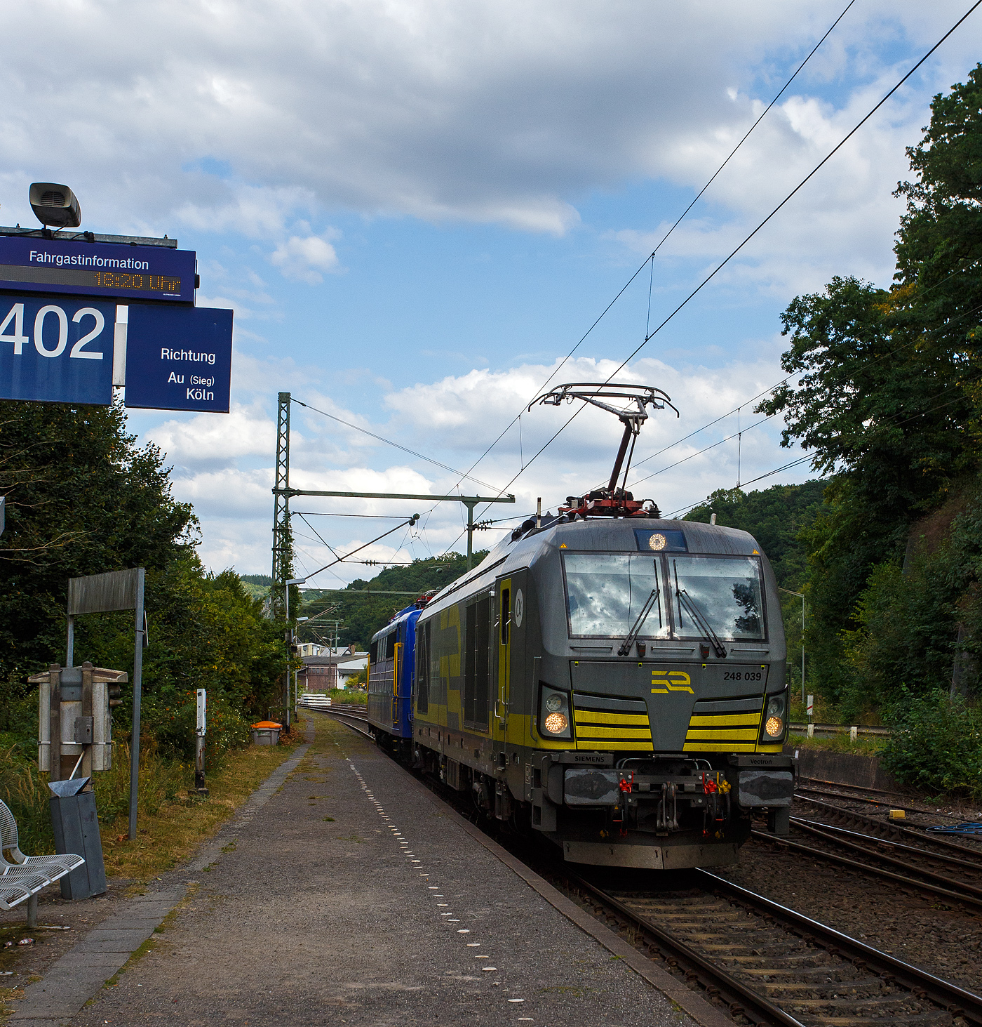 Die an die ERC.D GmbH (European Railway Company Deutschland, Nürnberg) vermietete SIEMENS Vectron Dual Mode 248 039-0 (90 80 2248 039-0 D-ATLU) der Alpha Trains Luxembourg s.à.r.l. fährt am 23 August 2025, mit der an die WRS Deutschland GmbH vermietete 151 033-3 (91 80 6151 033-8 D-SRI) der SRI Rail Invest GmbH im Schlepp, durch Scheuerfeld/Sieg in Richtung Köln.

Die SIEMENS Vectron DM 248 039 wurde 2023 von Siemens Mobility GmbH in München-Allach unter der Fabriknummer 23261 gebaut. Die ex DB 151 033-8 wurde 1974 von Krauss-Maffei AG in München-Allach unter der Fabriknummer 19652 gebaut.