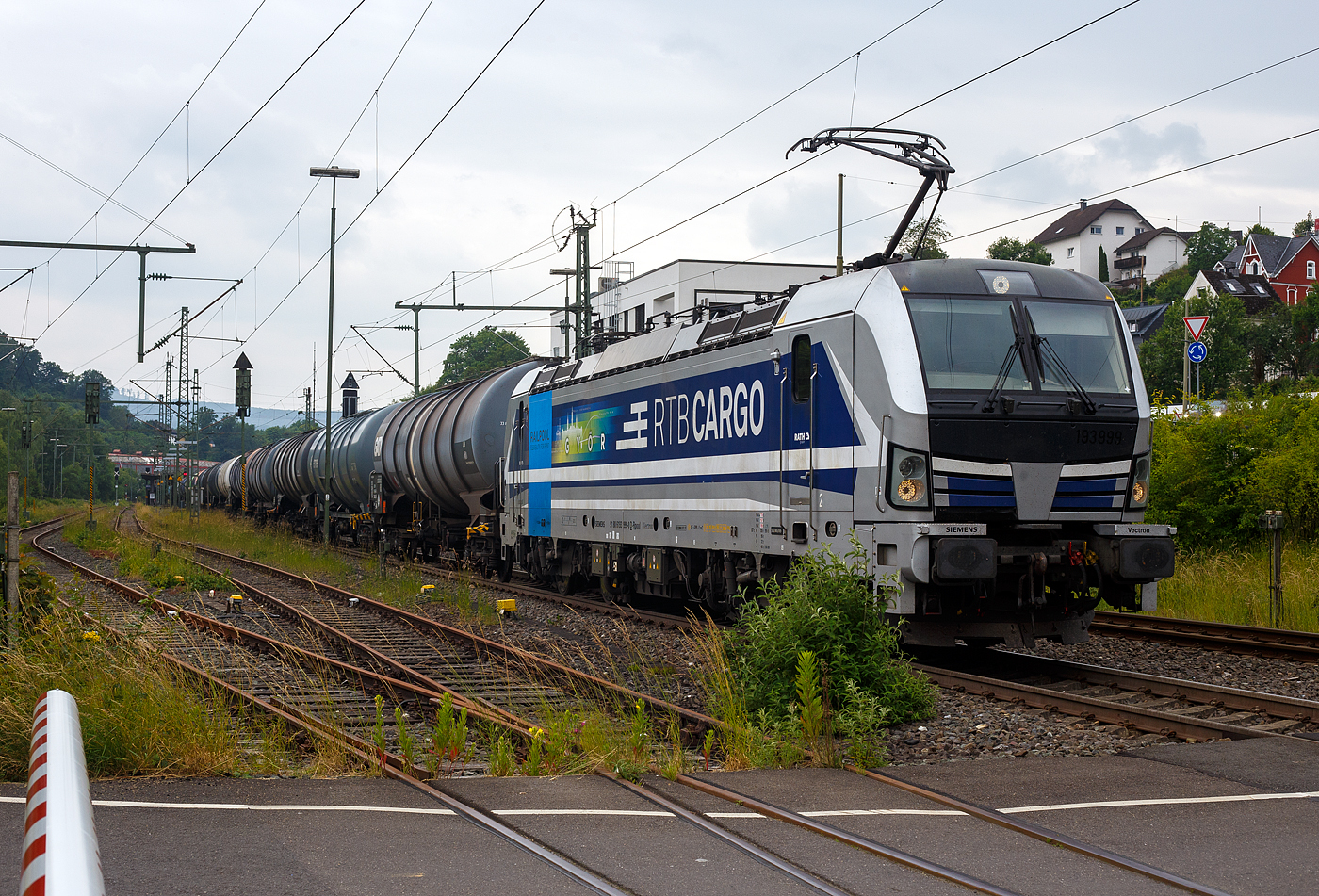 Die an die RTB Cargo - Rurtalbahn Cargo GmbH (RATH Gruppe) vermietete SIEMENS Vectron AC 193 999-0 „Győr“ (91 80 6193 999-0 D-Rpool) fährt am 10 Juni 2025 mit einem, laut Warntafel (30/1202) mit Heizöl oder Diesel beladenen, Kesselwagenzug durch Niederschelderhütte in Richtung Siegen 

Die Wechselstromlok (AC 15 kV 16,7 Hz und AC 25 kV 50 Hz) SIEMENS Vectron AC 193 999-0 wurde 2019 von Siemens Mobilitiy in München-Allach unter der Fabriknummer 22698. Sie ist als Vectron AC B16-2b ausgeführt und hat so die Zulassung für Deutschland, Österreich, Ungarn und Rumänien (D / A / H + RO). Sie hat eine Leistung von 6.400 kW (8.700 PS). 