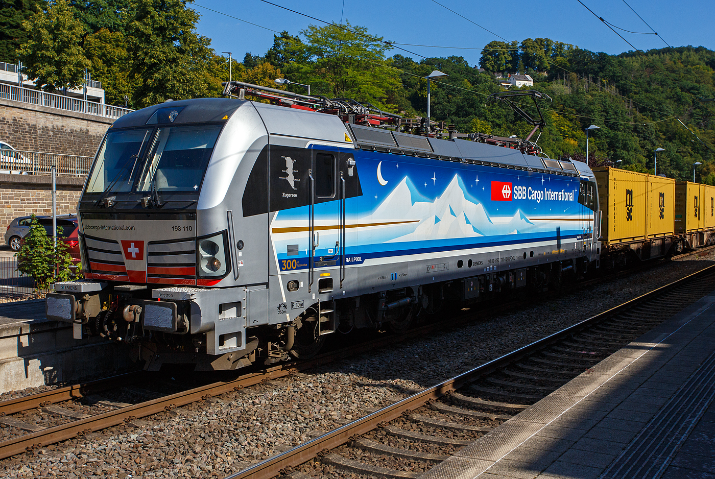 Die an die SBB Cargo International AG vermietete Siemens Vectron MS - 193 110  Zugersee  (91 80 6193 110-4 D-Rpool) der Railpool GmbH (München) fährt am 18 August 2025 mit einem Containerzug durch den Bahnhof Kirchen/Sieg in Richtung Siegen. 

Die SIEMENS Vectron MS (X4E) wurde 2023 von Siemens Mobility in München-Allach unter der Fabriknummer 23293 gebaut. Die mit 6.400 kW konzipierte Mehrsystemlok ist in der Variante A22 ausgeführt und hat so die und hat so die Zulassungen und entspr. Länderpakete für Deutschland, Österreich, Schweiz, Italien und die Niederlande (D / A / CH / I / NL), wobei z.Z. CH und I noch durchgestrichen sind. Sie ist die 300th Lokomotive der Railpool. 