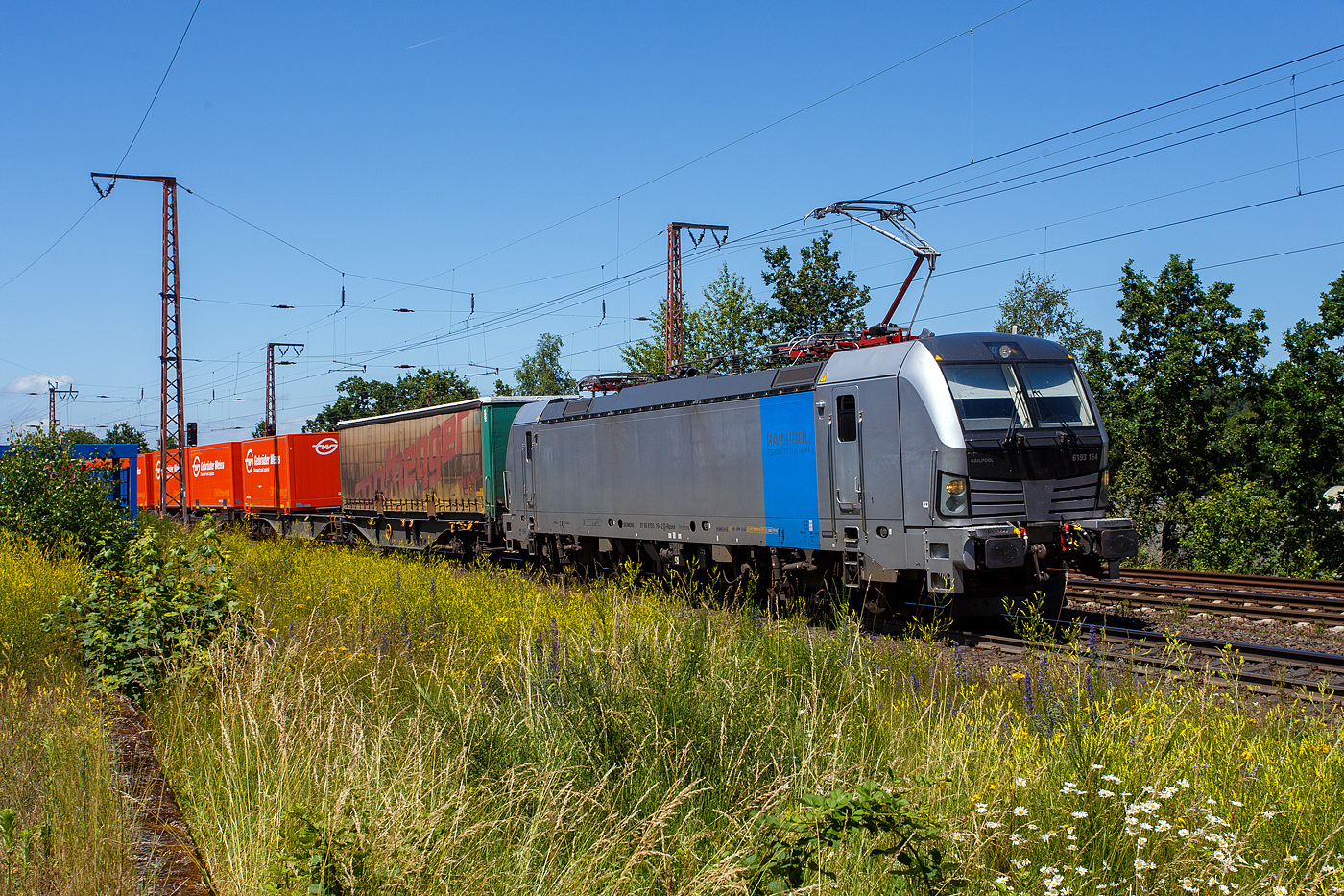 Die an die TX Logistik AG, Troisdorf (zur Mercitalia Group gehörend) vermietete SIEMENS Vectron AC 6193 154-2 (91 80 6193 154-2 D-Rpool) der Railpool GmbH (München) fährt am 28 Juni 2024 mit einem KLV-Zug durch Wilnsdorf -Rudersdorf (Kr. Siegen) in Richtung Süden.

Die Vectron Wechselstromlok (AC 15 kV 16,7 Hz und AC 25 kV 50 Hz) SIEMENS Vectron AC wurde 2023 von Siemens Mobilitiy in München-Allach unter der Fabriknummer 23499 gebaut. Sie wurde in der Vectron Variante AC B18 ausgeführt und hat so die Zulassung für Deutschland, Österreich, Schweden, Norwegen und Dänemark (D / A / S / N und DK). So besitzt die Variante AC B18 folgende  Zugsicherungssysteme:
ETCS BaseLine 3, sowie für Deutschland (PZB90 / LZB80 (CIR-ELKE I)), für Österreich (ETCS Level 1 mit Euroloop, ETCS Level 2, PZB90 / LZB80), 
für Schweden und Norwegen (ATC-2 (L10000)) und für Dänemark ZUB 123.
