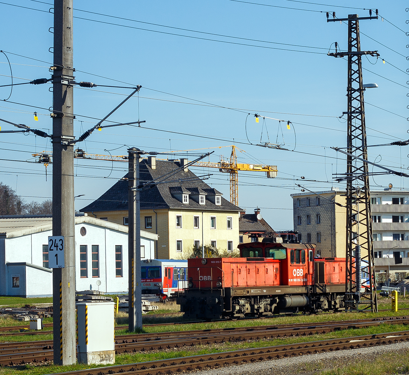 Die ÖBB 1063 013-7 (A-ÖBB 91 81 1063 013-7) ist am 05 April 2025 beim Bahnhof Attnang-Puchheim abgestellt.

Die Reihe 1063 der Österreichischen Bundesbahnen (ÖBB) bezeichnet vierachsige Elektrische Zweifrequenz-Universallokomotiven, die vorrangig für den Verschubdienst (Rangierdienst) vom Hersteller SGP - Simmering-Graz-Pauker in Graz von 1983 bis 1991 gebaut wurden. Die elektrischen Ausrüstungen wurden von ELIN, BBC, oder Siemens Wien geliefert. Die 1063 013-7 wurde 1986 von SGP in Graz unter der Fabriknummer 78948 gebaut.

Österreich setzte schon früher auf elektrische Lokomotiven im Verschubdienst. Als Folge der Ölkrise der 1970er Jahre sollten vermehrt elektrische anstatt Diesellokomotiven im Verschubdienst eingesetzt werden. Zudem wurden in diesem Jahrzehnt die letzten Dampflokomotiven in dieser Funktion abgestellt. Nach einer fast dreißigjährigen Beschaffungspause (zuletzt Lokomotiven der Reihe 1062, abgesehen von der Splittergattung 1067 in den 1960er Jahren) wurde die Reihe 1063 bei SGP in Auftrag gegeben, ihr Vorbild war eine Zechenlok der Ruhrkohle AG, die Henschel E 1200 (97 80 1200…).

1975 beschlossen die ÖBB, Leistungssteigerungen im ertragreichen Güterverkehr zu erzielen. Eine Höchstgeschwindigkeit von 80 bzw. 100 km/h wurde als ausreichend angesehen, denn es war viel wichtiger, die zeitintensive Zugbildung und -auflösung zu beschleunigen. Geeignete Lokomotiven dazu fehlten allerdings noch. Eine Lösung sah man in den neuen Drehstromlokomotiven E 1200 der Ruhrkohle AG von Henschel, deshalb wurde die Lokomotive RAG 1200 006 von den ÖBB 1979 intensiv getestet. Diese gilt somit als „Mutter“ der Baureihe 1063, von der die ÖBB zunächst fünf Exemplare bei Simmering-Graz-Pauker Graz bestellten. Nachdem sich diese bewährten, folgten später zwei weitere Lieferserien (006–037 und 038–050), jeweils mit technischen Unterschieden. Der elektrische Teil wurde von BBC, ELIN und Siemens geliefert. Die Lokomotiven 1063 005 und 006 wurden unfallbedingt ausgemustert. 

Die E-Lokomotive ÖBB Rh 1063 kommt sowohl im Verschubdienst, auf Abrollanlagen und im leichten Streckendienst zum Einsatz. Durch die Zweifrequenz-Technik (1063 001 bis 037), 15 kV / 16 2/3 Hz und 25kV / 50Hz, ist die Lok für den grenzüberschreitenden Verkehr zwischen Österreich, Ungarn, Tschechien und Slowakei geeignet.

Mechanischer Teil:
Die Lokomotiven der Reihe 1063 besitzt einen Mittelführerstand mit beidseitig etwa gleich langen Vorbauten, in denen die traktionstechnischen Baugruppen untergebracht sind. Führerstand und Vorbauten ruhen auf dem Hauptrahmen. Der Rahmen der Lokomotive stützt sich auf den beiden zweiachsigen Drehgestelle in Holmbauweise in vier Punkten mit je drei Schraubenfedern ab. Die Zugkraftübertragung von den Drehgestellen auf den Brückenrahmen erfolgt über tiefliegende Drehzapfen.

Elektrischer Teil:
Das kurze Dach trägt einen Einholm-Stromabnehmer (Bauart VII), den Hauptschalter und die Dachleitungen. Der Einphasenwechselstrom wird nach den Sekundärwicklungen des fremdbelüfteten und ölgekühlten Trafo gleichgerichtet und in Drehstrom umgewandelt. Dieser treibt die vier sechspoligen – als Käfigläufer ausgebildeten – Drehstromasynchronmotoren mit je 390 kW an. Die Steuerung erfolgt durch Vorgabe der Zug- beziehungsweise Bremskraft. Als Antrieb dient ein einseitiger Tatzlagerantrieb mit schrägverzahntem Getriebe mit 19:102 Zähnen. Alle Lokomotiven besitzen eine elektrodynamische Bremse mit 1200 kW Bremsleistung, eine selbsttätige Druckluftbremse und eine Federspeicherbremse. Die 1063 001 bis 037 sind außerdem zweifrequenzfähig und können auch unter 25 kV Wechselspannung mit 50 Hz eingesetzt werden.

TECHNISCHE DATEN:
Gebaute Anzahl: 50
Spurweite: 1.435 mm (Normalspur)
Achsformel: Bo’Bo’
Begrenzungslinie : UIC 505-1
Länge über Puffer: 15.700 mm
Drehzapfenabstand: 8.300 mm
Achsabstand in Drehgestell:  2.800 mm
Raddurchmesser:  1.145 mm (neu) / 1.065 mm (abgenutzt) 
Dienstgewicht: 82 t (1063 001-004: 78 t)
Radfahrmasse: 20,5 t (1063 001-004: 19,5 t)
Meterlast: 5.223 kg (1063 001-004: 4.968 kg)
Höchstgeschwindigkeit: 100 km/h 
Dauerleistung:  1.600 kW
Maximalleistung: 2.000 kW 
Anfahrzugkraft: 260 kN
Stromsysteme: 15kV/16,7Hz (1063 001-004, 007-009, 011-037,047 zus.  25 kV, 50 H)
Antriebsart: 4 Drehstrom Fahrmotoren und Tatzlagerantrieb
Zugelassen für Streckenklasse: D2 oder höher
Kleinster befahrbarer Gleisbogen (Vmax= 10 km/h): R = 100 m
Bremsbauart: KE-GPR-E m Z
Dynamisches Bremssystem: Elektrodynamische Rückspeisebremse
Max. Bremskraft der dynamischen Bremse: 115 kN

Quellen: ÖBB, ÖBB-Produktion GmbH und Wikipedia
