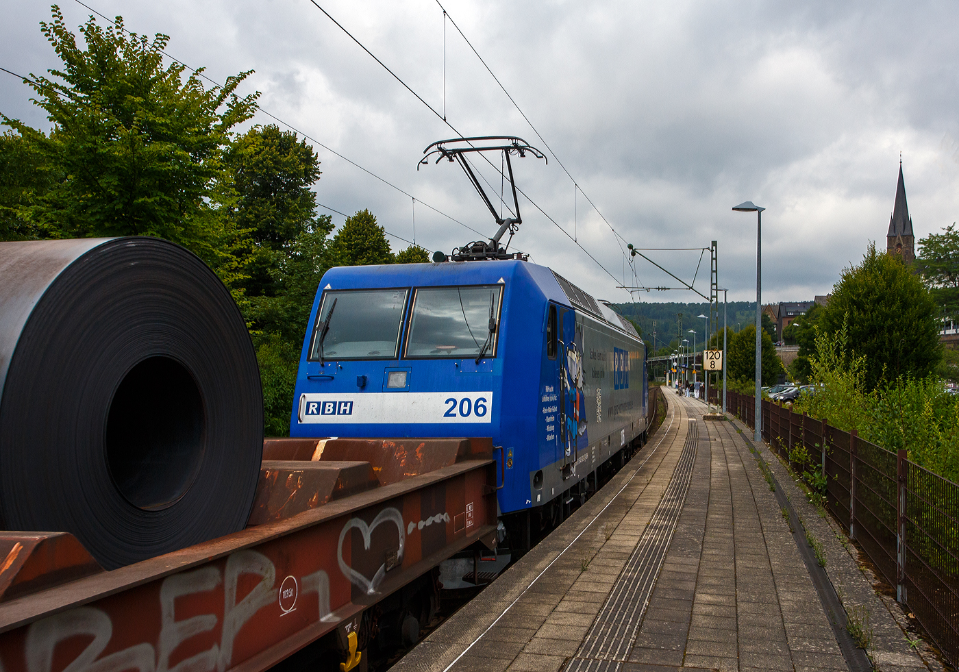 Die RBH 206 / 145-CL-206 / 145 102-0 (91 80 6145 102-0 D-RBH) der RBH Logistics GmbH, Gladbeck, ex RBH - RAG Bahn and Hafen GmbH, fährt am 28 Juli 2025 mit einem offenen Warmband-Coilzug durch den Bahnhof Kirchen/Sieg in Richtung Siegen.

Die TRAXX F140 AC wurde 2001 von ADtranz (ABB Daimler-Benz Transportation GmbH) / Bombardier Transportation in Kassel unter Fabriknummern 33850 gebaut.
