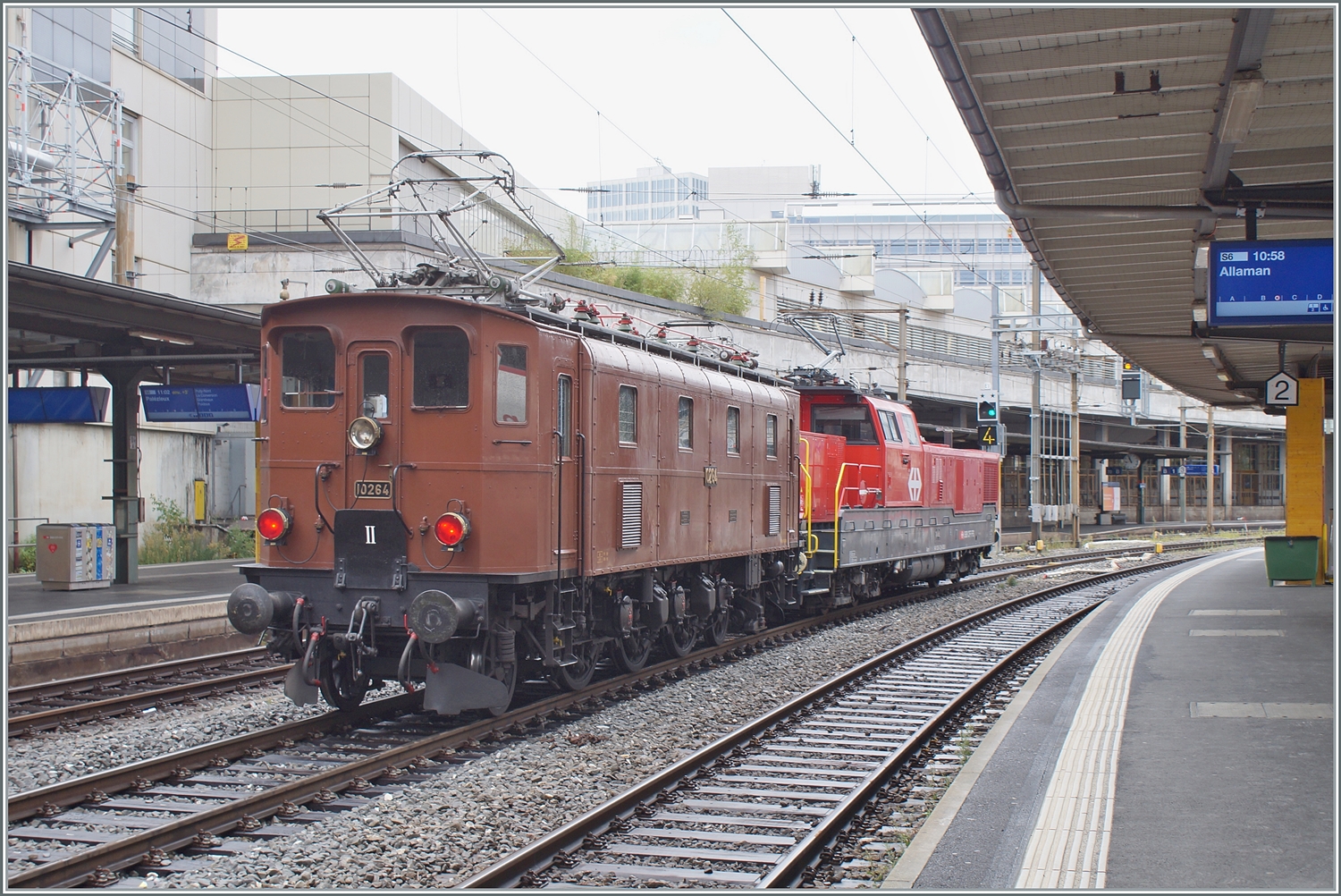 Die SBB Historic Ae 3/6 III 10264 schiebt in Lausanne ein mächtiges ETCS Gerät in Form einer Aem 940 vor sich her. Die Lok ist wohl auf der Rückfahrt vom Dépôt Fest in Olten nach St-Maurice. In den Jahren 1925 und 1926 wurden die kleine Serie der elf Ae 3/6 III 10261 - 10271 gebaut, die 89 Tonnen schwere Lok hatte eine Höchstgeschwindigkeit von Km/h 90 und 1800 PS. Die Lok wurde entwickelt, da recht kurzen Ae 3/5 bei hoher Geschwindigkeit schlechte Fahreigenschaften aufwiesen, somit wurde die Konstruktion der Ae 3/5 einfach verlängert und als Ae 3/6 III in Dienst gestellt. Interessanterweise wurden die letzten Ae 3/5 erst 1983 ausrangiert, die letzte Ae 3/6 III 1980. 2

28. August 2023