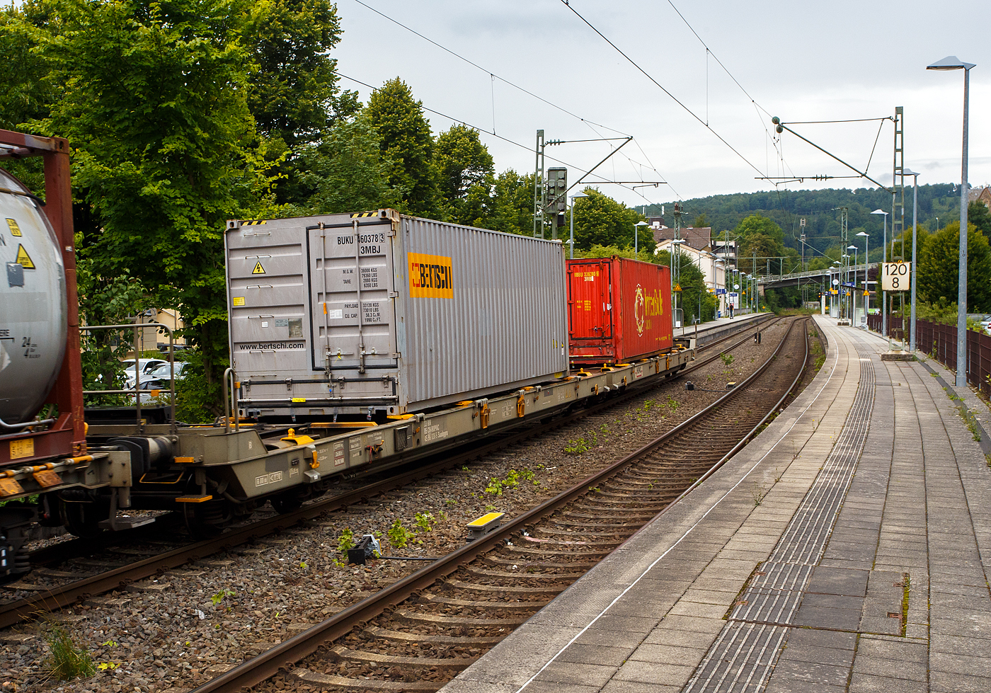 Eher ein Exot unter den Taschenwagen, der niedriggelegte achsachsige Doppelwagen Mega I, 33 85 459 6 036-5 CH-HUPAC, der Gattung Saadggns, der HUPAC Intermodal SA (Chiasso), am 01 August 2025 im Zugverband bei einer Zugdurchfahrt im Bahnhof Kirchen/Sieg, hier beladen mit zwei 30`-Container. Die Wageneinheit ist über eine sogenannte Kurzkupplung realisiert. So ist es einer 2x4-achsigen Wageneinheit, also vier Drehgestellen (acht Achsen) pro Wageneinheit.

Diese Wagen wurden in einer Serie von 45 Stück 1994 von der Ferriere Cattaneo SA in Giubiasco (Tessin/CH). Leider sind im Netz keine Datenblätter vorhanden, so kann ich den Wagen nur nach den Anschriften und eigener Sichtung beschreiben.

Diese Güterwagen sind zum Transport von kranmanipulierbaren Sattelaufliegern und genormten Wechselbehältern / Containern an allen europäischen Eisenbahnstrecken mit Normalspurweite bestimmt, auch bekannt als intermodaler Verkehr. Durch die niedrig gelegte Ladefläche können C 70-400 kodifizierte Jumbo-Wechselbehälter bis Norditalien und High-Cube-Container bis Süditalien auf der Gotthardstrecke transportiert werden.

TECHNISCHE DATEN:
Spurweite: 1.435 mm (Normalspur)
Länge über Puffer: 35.570 mm
Drehzapfenabstände: 13.300 mm /4.940 mm / 13.300 mm
Achsabstand in den Drehgestellen: 1.800 mm
Laufraddurchmesser: 840 mm (neu)
Ladelänge: 2 x 15.850 mm (ca. 2 x 52`)
Höhe der Ladeebene für Container/WB über SOK: 940 mm
Höhe der Tasche (für Sattelanhänger) über SOK: 270 mm
Eigengewicht: 33.000 kg
Max. Zuladung: 92,0 t (ab Streckenklasse A)
Max. Gewicht eines Sattelanhängers (je Wageneinheit): 38,5 t
Höchstgeschwindigkeit: 100 km/h (beladen) / 120 km/h (leer)
Bremse: O-GP-A (K) – 2 x 46 t
Bremssohle: Jurid 838 (Komposit-Bremssohlen)
Feststellbremse: Ja, jeweils an den mittleren Drehgestellen
Kleinster befahrbarer Gleisbogen: R 80 m
Verwendungsfähigkeit: RIV (Regolamento Internazionale Veicoli)

Die Bedeutung der Gattungs- und Kennbuchstaben (hier Saadggns):
S - Drehgestell-Flachwagen in Sonderbauart
aa - mit acht oder mehr Radsätzen
d - für den Transport von Straßenfahrzeugen eingerichtet
gg - für den Transport von Containern über 60 Fuß eingerichtet
n - mit sechs oder mehr Radsätzen höchste Lastgrenze über 75 
s - Höchstgeschwindigkeit (beladen) bis zu 100 km/h

