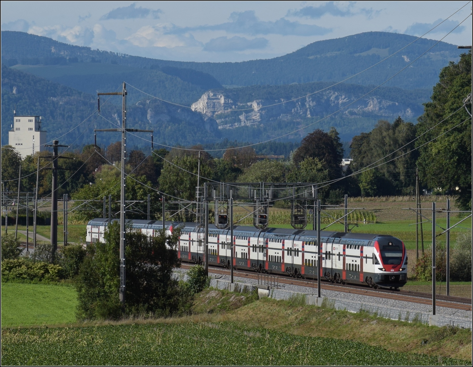 Ein unbekannt gebliebener RABe 511 0xx und RABe 511 120 in Richtung Burgdorf an der Önz bei Bettenhausen. Im Hintergrund ist noch die Klus nach Balsthal am Felsen gut zu erkennen. Dahinter rechts das 1157 m hohe Chellenchöpfli nebst dem Wasserfallen und links angeschnitten der 1203 m hohe Vogelberg am Passwang. Dort hätte die nie realisierte Wasserfallenbahn ihren Tunneldurchstich bekommen. September 2022.