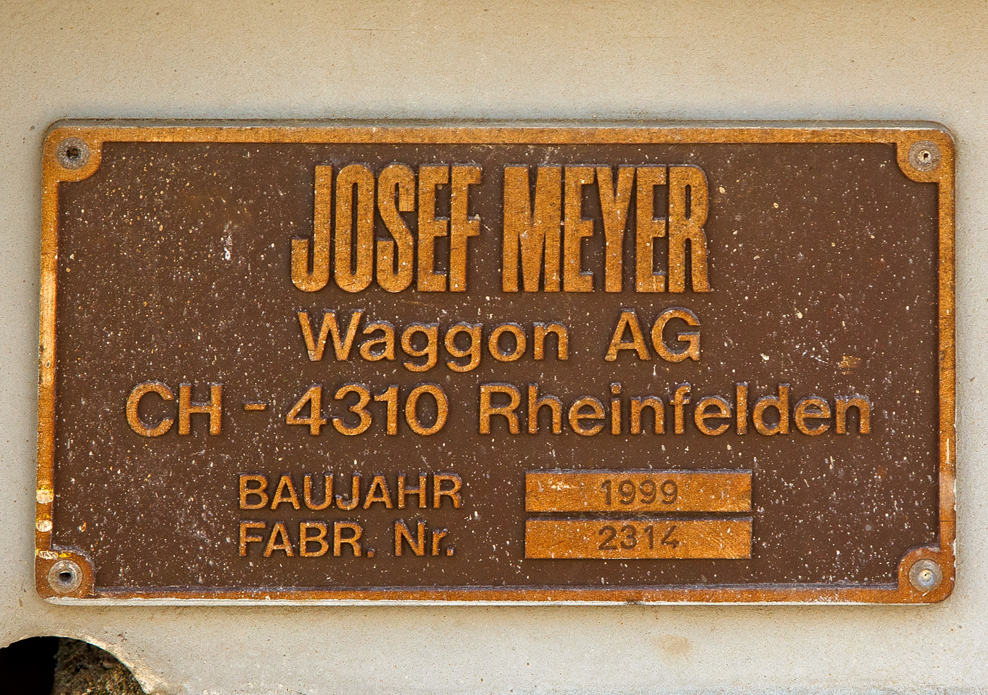 Fabrikschild Josef Meyer Waggon AG in Rheinfelden (CH), von dem vierachsigen Drehgestell-Tiefbett-Flachwagen als Dienstgüterwagen MOB X 775 der Montreux-Berner Oberland-Bahn, ex RhB Sbk-v 7705, abgestellt am 26.05.2023 in Vevey.