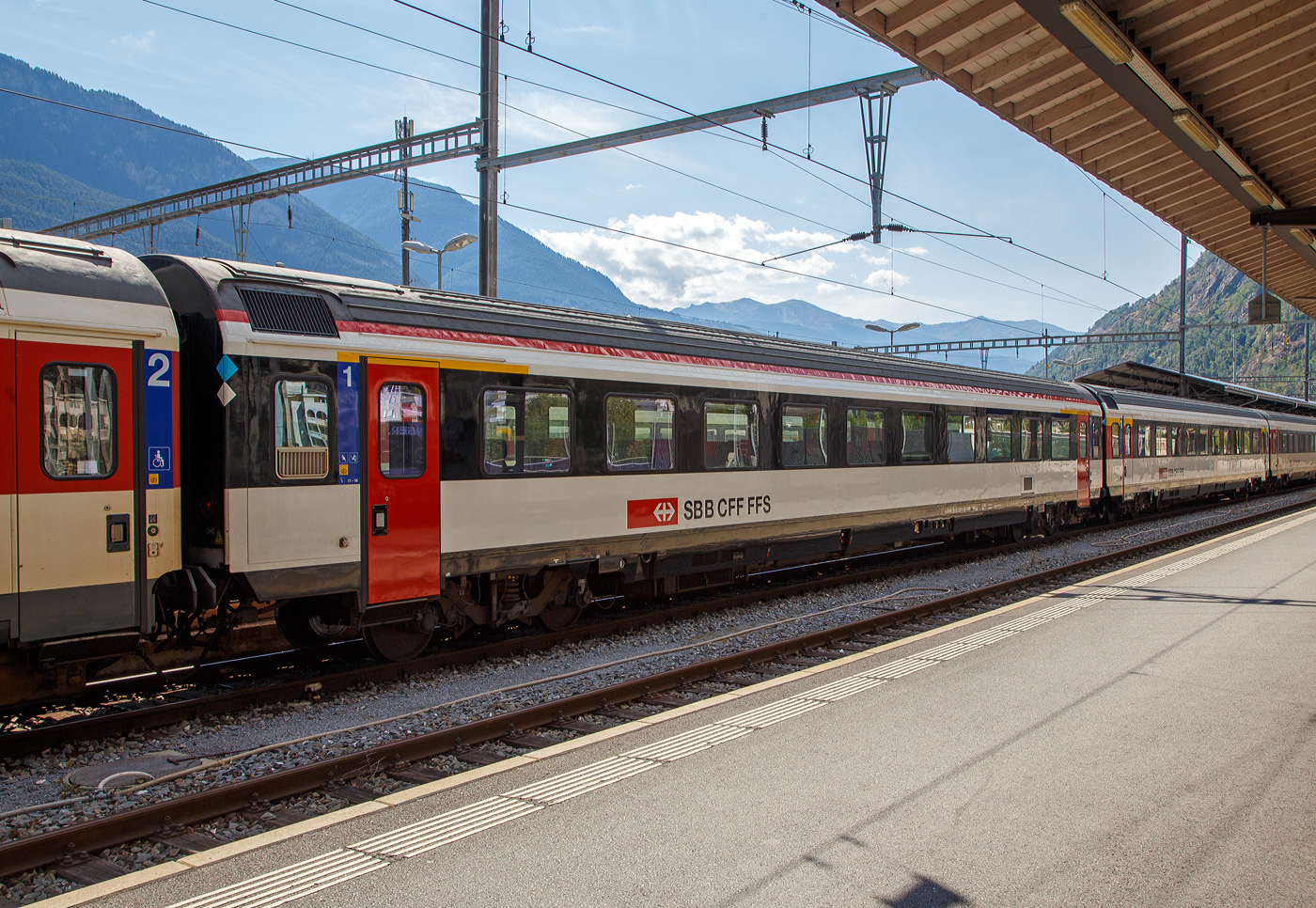 Frisch revidierter SBB IC-Reisezugwagen der ersten Wagenklasse (Einheitswagen IV) A 50 85 10-75 173-0 CH-SBB eingereiht in einen IR 90 nach Genève-Aéroport (Genf Flughafen) am 07 September 2021 im Bahnhof Brig. Die Revision R2 war am 23.04.2021.

Nach den eher durchwachsenen Erfahrungen mit den Einheitswagen III entwickelte die Waggon-Industrie zusammen mit den SBB die neuen Einheitswagen IV. Von den ursprünglich grün-steingrau lackierten Wagen wurden von 1981 bis 1992 über 500 Stück gebaut.  

Zwischen 1995 und 1998 wurden 300 Einheitswagen IV pendelzugfähig gemacht. Und dazu wurden 90 neue IC Steuerwagen Bt beschafft, die den Wagen anglichen waren. Ab 2000 wurden die Wagen teilweise auf eine Höchstgeschwindigkeit von 200 km/h (vorher 160 km/h) ertüchtigt, aber nicht dieser. Die Toiletten erhielten eine Vakuumeinrichtung, da offene Systeme (Fallrohrtoiletten) auf der NBS behördlich verboten sind. Nach dem Umbau in Pendelzugwagen haben die Wagen die Bezeichnung -75 statt -73. Für 200 km/h geeignete Pendelzug-Wagen erhalten die Bezeichnung -95. 

Seit 2021 erhalten die EW IV ein neues Farbkleid, das am ehesten durch die Türen in RAL 3000 (Feuerrot) auffällt. Damit werden Vorschriften des Behindertengleichstellungsgesetzes betreffend Sichtbarkeit und Kontrast der Türbereiche umgesetzt. Außerdem wird die seitliche Unterbodenverkleidung, die bisher grau war, sowie auch das Fensterband an den Wagenenden (vorher rot) nun neu schwarz lackiert, um damit dem Design der Neubaufahrzeuge zu entsprechen. Zudem ziert eine neue, durchgehende rote Längslinie den Übergang von der Seitenwand zum Dach. Die Unterschiede der Farbkleider sind hier im Bild gut zusehen 

Gleichzeitig, aber unabhängig vom oben genannten Neulackierungs-Programm werden auch die Türen umgebaut. Diese werden vom alten pneumatischen Antrieb auf elektrischen Antrieb umgebaut.

TECHNISCHE DATEN:
Spurweite: 1.435 mm (Normalspur)
Länge über Puffer: 26.400mm 
Drehzapfenabstand: 18.600 mm
Höchstgeschwindigkeit: 160 km/h
Eigengewicht: 42 t
Bremse: O-PR+Mg (D)
Sitzplätze: 60 in der 1. Klasse
Toilette: 1 Toiletten (geschlossenes Systeme/ Vakuumsystem)
Zulassung: NBS
