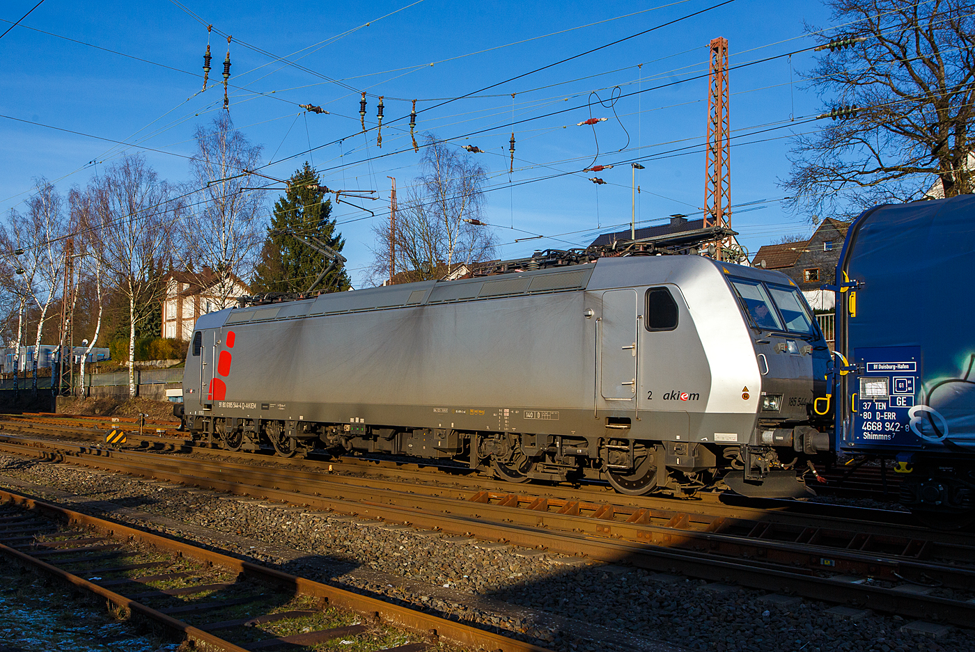 Heute am 8 Januar 2024 fegte ein bitter kalter Wind, aber endlich kam nochmal die Sonne hervor, so fuhren wir trotz der Bauerndemos nach Kreuztal, zudem ist ab morgen wegen dem GDL-Streik der Bahnverkehr lahm gelegt. Wir hatten den richtigen Weg gewählt und kamen zügig hin und zurück.

Die mit DACH-Zulassung (Deutschland, Österreich und Schweiz) an die DB Cargo AG vermietete Akiem 185 544-4 (91 80 6185 544-4 D-AKIEM), ex MRCE Dispolok (91 80 6185 544-4 D-DISPO), fährt mit einem Übergabezug (leere Coil-Wagen) vom Rbf Kreuztal in Richtung Hagen los. 

Die TRAXX F140 AC1 wurde 2005 von Bombardier Transportation GmbH in Kassel unter der Fabriknummer 33729 gebaut und an die MRCE - Mitsui Rail Capital Europe geliefert. An die AKIEM SAS wurde sie 2023 verkauft. Sie hat die Zulassungen für Deutschland, Österreich und die Schweiz (D/A/CH).
