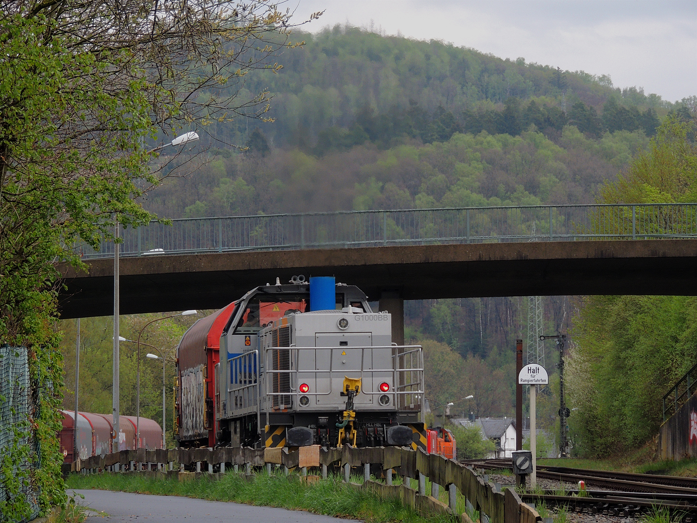 Hochbetrieb in Herdorf am 23 April 2025: 
Durch die vergangenen Osterfeiertage braucht es wohl wieder Nachschub. Die KSW (Kreisbahn Siegen-Wittgenstein) kommt im Sandwich mit einem sehr langen und somit schweren Coilzug, von via Betzdorf/Sieg kommend, und erreicht den KSW-Rangierbahnhof (Betriebsstätte FGE - Freien Grunder Eisenbahn).

Hier am Zugschluss die nachschiebende KSW 47 (92 80 1271 027-5 D-KSW), ex D 2 der HFM, eine Vossloh G 1000 BB, vorne als Zuglok die KSW 44 (92 80 1271 004-4 D-KSW) auch eine MaK G 1000 BB. Im Rbf wird der Zug geteilt, da er für die Weiterfahrt sonst zu lang wäre, und die KSW 44 zieht den ersten Teil weiter zu den Schäfer Werke KG am Pfannenberg in Neunkirchen-Salchendorf. 

Die KSW-Bahnstrecke Herdorf–Pfannenberg-(ehem. Unterwilden) ist eine rund 8 km lange Nebenbahn, bekannt ist sie auch als „Talbahn“. Die Strecke wurde von der 1904 gegründeten Freien Grunder Eisenbahn AG betrieben. Die gebliebenen Gleise und Anlagen sind seit 1970, als Betriebsstätte FGE - Freien Grunder Eisenbahn. Teil der heutigen Kreisbahn Siegen-Wittgenstein.

Später kam dann noch die KSW 43 (92 80 1273 018-2 D-KSW), die asymmetrische Vossloh G 2000 BB, mit einem langen Coilzug von Duisburg an.
