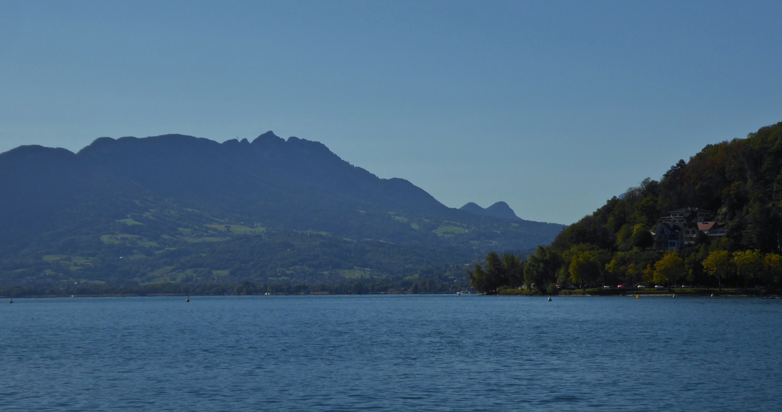 Impressionen von einer Bootsrundfahrt über den See von Annecy, 
weiter Blick über den See und auf hügeliges Gelände. 09.2022
