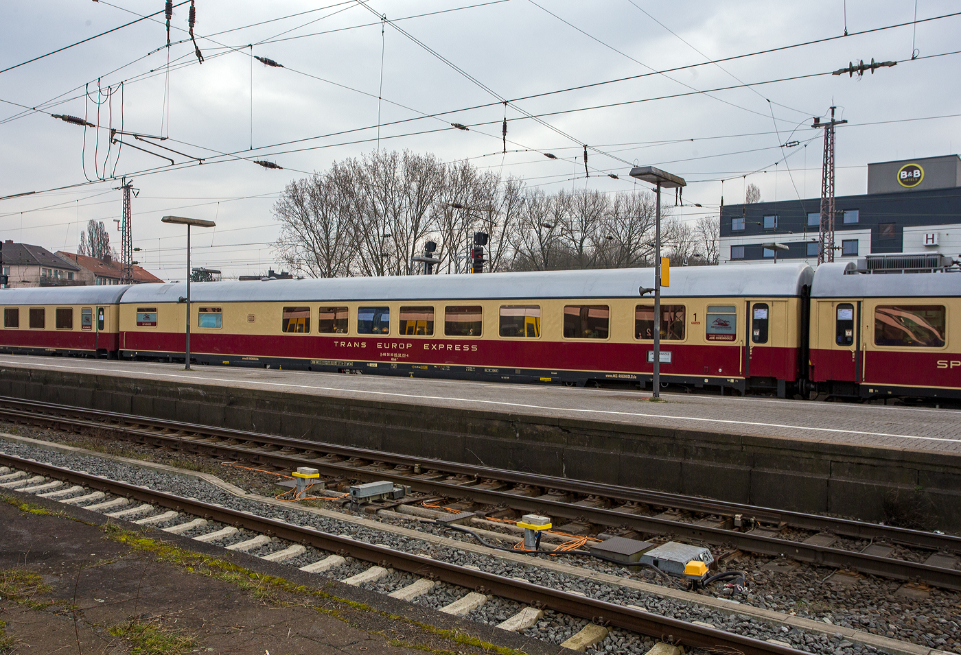 Klimatisierter 1. Klasse Halbspeisewagen der Gattung/Bauart ARmh 217, D-AKE 56 80 85-92 151-4, der AKE-Eisenbahntouristik – Jrg Petry e.K. (Gerolstein) am 10 Mrz 2024 im Hbf Osnabrck, eingereiht im Zugverband in den 1. Klasse-Sonderzug AKE RHEINGOLD (vom 10 bis 14 Mrz 2024) von Koblenz via Hamburg, Bremen, Husum und Westerland auf Sylt nach List auf Sylt. 

Der Wagen wurde 1969 von Waggonfabrik Wegmann & Co. in Kassel gebaut und als D-DB 51 80 84-80 251-2 ARmh 217 an die Deutschen Bundesbahn geliefert. Im Jahr 2006 wurde er an Regentalbahn verkauft, wo er als 56 80 85-92 151-4 D-RBG BRmh gefhrt wurde, 2013 ging er an die Pressnitztalbahn, neue Nummer 56 80 85-92 151-4 D-PRESS ARmh 217 und 2015 wurde er an die Vulkaneifel-Bahn wo er nun wieder die Bezeichnung 56 80 85-92 151-4 D-AKE ARmh 217 fhrt.

Allgemeines zu den Halbspeisewagen:
Die Deutsche Bundesbahn fhrte ab 1966 fr die damaligen F-Zge Halbspeisewagen der Typen Armz 211, ARmh 217 und Armz 218 ein. Diese Wagen mit einer Lnge von 27,5 m bestehen aus einer Kche, dem Speiseraum und Sitzabteilen der 1. Klasse. Die Wagen waren zunchst in innerdeutschen und internationalen F-, D- und TEE-Zgen im Einsatz. Ab September 1971 kam auch der neu eingerichtete IC-Verkehr hinzu. Die Einstiege mit Drehfalttren befinden sich an einem Wagenende. Dort sind auch die Toilette und eine Kofferablage installiert. Es folgt ein Groraum 1. Klasse mit 18 Pltzen, bestehend aus Einzelsitzen und zustzlichen Esstischen. Im anschlieenden Speiseraum knnen Reisende an 30 Pltzen bedient werden. Somit verfgt der Wagen insgesamt ber 48 Sitzpltze. Der Wirtschaftsbereich besteht aus Bfett, Kche und Splraum. Die Wagen wurden mit gasbeheizten Herden oder Elektroherden ausgestattet. Je eine Schiebetr in den Seitenwnden im Bereich der Kche dient zum Beladen des Fahrzeugs. Der ARmh 217 besitzt seit 1990 eine RIC-Zulassung fr 200 km/h (fr viele Lnder). Daher kommt der Wagen vornehmlich bei den Fahrten mit dem historischen TEE-Rheingold zum Einsatz. Die vorhandene Dampfheizung ermglicht aber auch Einstze bei Dampfsonderfahrten.

TECHNISCHE DATEN:
Lnge ber Puffer: 27.500 mm
Wagenkastenlnge: 27.200 mm
Wagenkastenbreite: 2.805 mm
Hhe ber Schienenoberkante: 4.050 mm
Drehzapfenabstand: 19.500 mm
Achsstand im Drehgestell: 2.500 mm
Drehgestellbauart: Minden-Deutz 367
Leergewicht: 51 t
Hchstgeschwindigkeit: 200 km/h (bei Ablieferung 160 km/h bis 1990)
Sitzpltze: 18  im 1. Klasse Groraum / 30 im Speiseraum
Heizungsbauart: Klimae
Energieversorgung: Zentrale Energieversorgung aus der Zugsammelschiene

Die Geschichte von diesem TEE/IC-Halbspeisewagen ARmh 217  D-AKE 56 80 85-92 151-4 (Quelle AKE Rheingold):
Der Wagen wurde von der Waggonfabrik Wegmann & Co. in Kassel gebaut und am 17.04.1969 mit der Wagennummer 51 80 84-80 251-2 in Dienst gestellt. Er gehrte zu einer Gruppe von 25 Wagen, die in vier Serien zwischen 1966 und 1970 geliefert wurden. Ihre zulssige Hchstgeschwindigkeit betrug damals160 km/h.

Diese Bauart wird als „Halbspeisewagen“ bezeichnet, weil sie im Gegensatz zu den „Vollspeisewagen“ einen verkleinerten Restaurant- und Wirtschaftsteil besitzt. Dafr wurde in der vorderen Wagenhlfte ein 1. Klasse-Groraum vorgesehen, der bei Bedarf als weiterer Speiseraum hergerichtet werden kann.

Alle Wagen hatten zu Beginn eine Lackierung in blau fr die 1. Klasse bzw. rot fr den Speisewagen-Bereich, was ihnen bald den Spitznamen „Kakadu“ einbrachte. Whrend die meisten dieser Fahrzeuge ab 1971 in die TEE-Farben beige/rot umlackiert wurden, behielt dieser Wagen sein ursprngliches Farbkleid noch bis 1983.

Im Gegensatz zu den anderen vollelektrischen Speisewagen wird hier auf einem Gasherd gekocht, wegen des hohen Stromverbrauchs konnte auch keine elektrische Geschirrsplmaschine eingebaut werden. Dafr kann der Wagen aufgrund seiner weitgehend autarken Energieversorgung in allen europischen Bahnstromsystemen eingesetzt und auch problemlos von einer Dampflok befrdert werden.

Sein Einsatzgebiet war dadurch uerst vielfltig, zunchst in Fernschnellzgen, ab 1971 im neuen, damals noch erstklassigen IC-Netz. Hinzu kamen TEE-Zge, hochwertige nationale und internationale Schnellzge, Autoreisezug-Dienste, Sonderzge zur Hannover-Messe und bis 1989/90 einige Transitzge zwischen der Bundesrepublik und Berlin (West). Dieser  Wagen war u.a. in Amsterdam, Brssel, Paris, Strasbourg und Mailand anzutreffen, lief im legendren „Orient-Express“ nach Wien und fhlte sich auch an der franzsischen Atlantik- und Mittelmeerkste wohl.

1983 wurde er grundlegend aufgearbeitet und erhielt dabei u.a. neue Fenster, die mit besserer Abdichtung vor Korrosion schtzten, neue Sitzbezge, stabilere Tische im Groraum 1. Klasse und auch eine Lackierung in den TEE-Farben. 1991 erfolgte ein Anstrich in den neuen IC-Produktfarben orientrot mit pastellviolettem Absetzstreifen, dann erhielt er die verkehrsrote Farbgebung und auch das ICE-Farbkleid erlebte er 2002 noch.

Ab 1990 war der Wagen fr eine Hchstgeschwindigkeit von 200 km/h zugelassen. 1999 wurde eine neue Kche eingebaut, die Sitze im Speise- und Groraum erhielten einen Polsterstoff in gediegenem Blau. Zuletzt lief er im EC „Wawel“ zwischen Hamburg und Breslau. Im Dezember 2005 wurde dieser Wagen bei der DB AG ausgemustert, erhielt anschlieend seine „Kakadu“-Lackierung zurck und wurde fortan von der Regentalbahn AG in den bayerischen ALEX-Zgen eingesetzt. Ab 2008 lief er bei der Pressnitztalbahn GmbH berwiegend in Sonderzgen, wurde aber von Dezember 2009 bis Mrz 2010 auch fr den Eurobahn-Ersatzverkehr des RE 13 zwischen Hamm und
Mnchengladbach verwendet.

2012 wurde dieser Wagen von der Vulkan-Eifel-Bahn bernommen, 2015 wieder in den TEE-Farben lackiert und ist seitdem in den Wagenpark des historischen „Rheingold“ der AKE-Eisenbahntouristik eingestellt.
