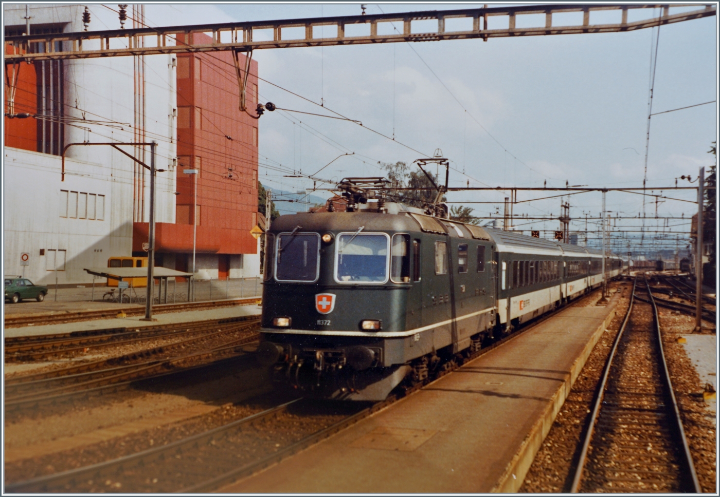 Noch eine BoBo: die SBB Re 4/4 II 11372 hat schon eckige Scheinwerfer, wurde aber noch in Grün in Dienst. 
Die Re 4/4 II 11372 fährt ohne Halt mit ihrem IC 124 durch den Bahnhof von Aarau. 

30.Sept. 1984