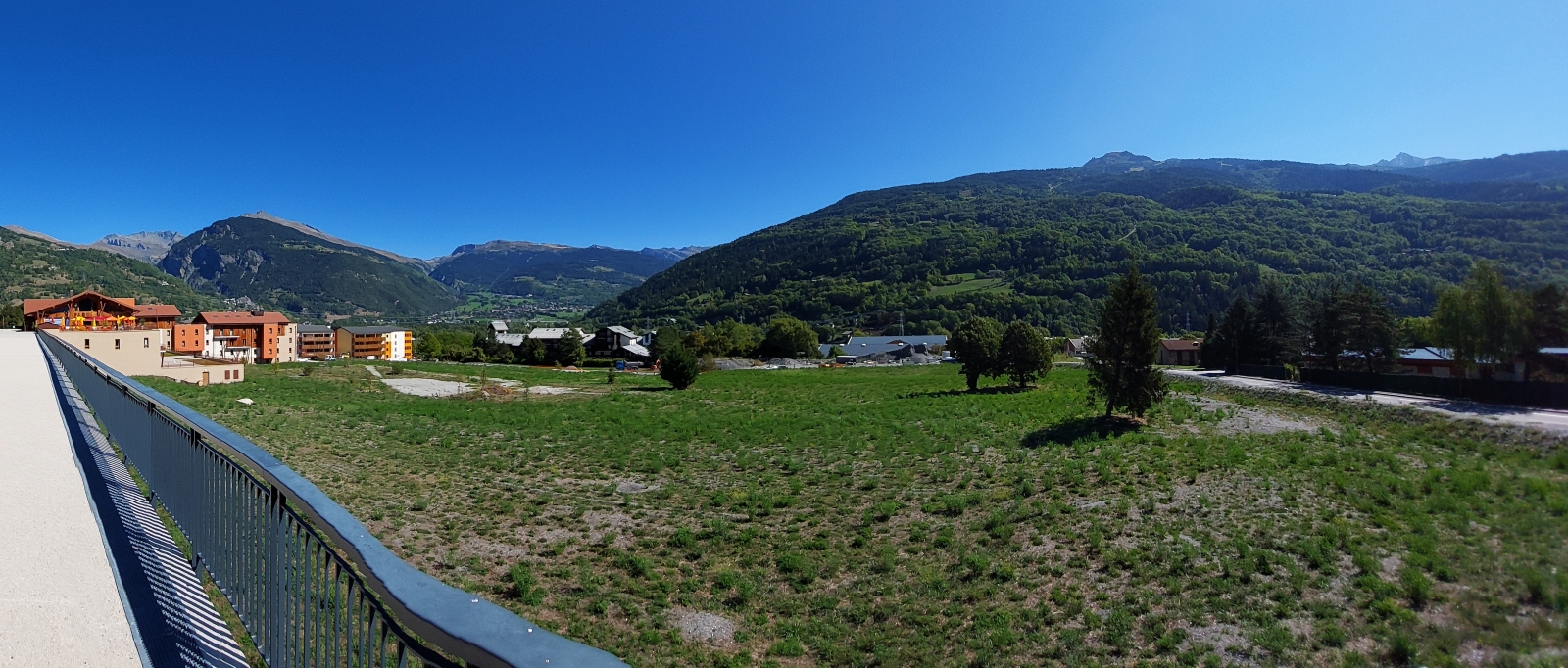 Panoramafoto aus Bourg St.-Maurice, das ganz von Bergen umgeben ist, zusehen ist auch die Linie der Standseilbahn die in das Wintersportgebiet „Les Arcs“ hochfährt. 09.2022