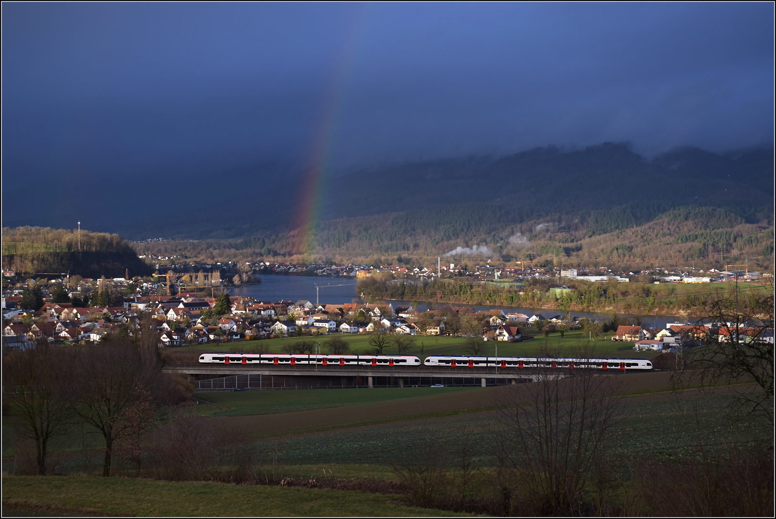 Schechtwetter in Mumpf. 

Eine Doppeltraktion Flirt RABe 523 unter einem Hochrhein-Regenbogen. Februar 2026.