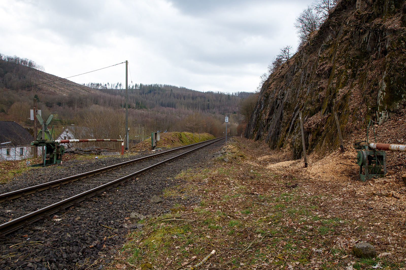 St�ndig geschlossene alte Schranke (ehemalige Anrufschranke) bei km 87,8 (bei Herdorf-Sassenroth) der Hellertalbahn (KBS 462 / Strecke 2651), hier am 18.03.2023. Bis 1987 war der Abschnitt Betzdorf–Herdorf noch zweigleisig. 

Auch wenn hier mindestens bis zum kleinen Fahrplanwechsel im Juni 2023, wegen dem Felsstutz am 23.12.2022, kein Zug zwischen Betzdorf und dem Hp K�nigsstollen (Herdorf) f�hrt, ist und wird die Strecke nun gut freigeschnitten.
