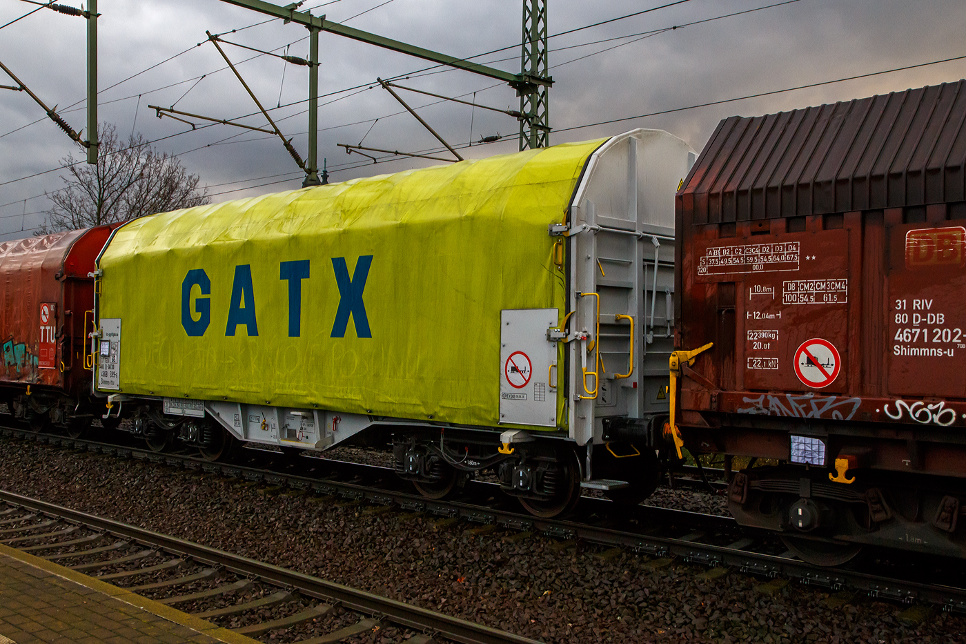 Vierachsiger Drehgestell-Flachwagen mit verschiebbarem Planenverdeck und Lademulden für Coiltransporte, 37 80 4668 599-6 D-GATED, der Gattung Shimmns-ttu, der GATX Rail Germany GmbH, am 07.12.2022 im Zugverband bei einer Zugdurchfahrt im Bahnhof Dresden-Strehlen. Der Waggonvermieter GATX (General American Transportation Corporation) ist eine US-amerikanische Leasinggesellschaft für Schienenfahrzeuge mit Sitz in Chicago. GATX wurde 1898 gegründet und ist seit 1916 an der New Yorker Börse notiert.

Diese Wagen sind speziell für den Transport witterungsempfindlicher Blechrollen (Coils) bestimmt. Er besitzt feste Stirnwände, 5 fest im Untergestell eingebaute Lademulden. Die Wagenabdeckung erfolgt mit einer PVC-beschichteten Gewebeplane, die auf 11 Rohrrahmen aufliegt. Über Laufwagen ist das Planendach in Wagenlängsrichtung verschiebbar. Die Verriegelung des Planendaches an den Stirnwänden erfolgt über eine 4-Punkt-Zentralverriegelung, die sowohl vom Erdboden als auch von der Rampe aus bedient werden kann. Das Planenverdeck lässt sich an einem Wagenende so weit zusammenschieben, dass ca. 2/3 der Ladefläche zur Beladung freigegeben wird. Hierdurch ist eine einfache Beladung des Wagens sowohl von oben als auch von der Seite aus möglich. 

TECHNISCHE DATEN:
Spurweite: 1.435 mm
Achsanzahl: 4 (in 2 Drehgestelle)
Länge über Puffer: 12.040 mm
Länge der Ladefläche: 10.800 mm
Drehzapfenabstand: 7.000 mm
Achsabstand im Drehgestell: 1.800 mm
Eigengewicht:  21.770 kg
Höchstgeschwindigkeit: 100  km/h (beladen) / 120 km/h (leer)
Maximales Ladegewicht: 68,2 t (Streckenklasse D4)
Kleinster bef. Gleisbogenradius: 35 m
Bauart der Bremse: KE-GP-A (K)
Bremssohle: C 810
Intern. Verwendungsfähigkeit: TEN - GE