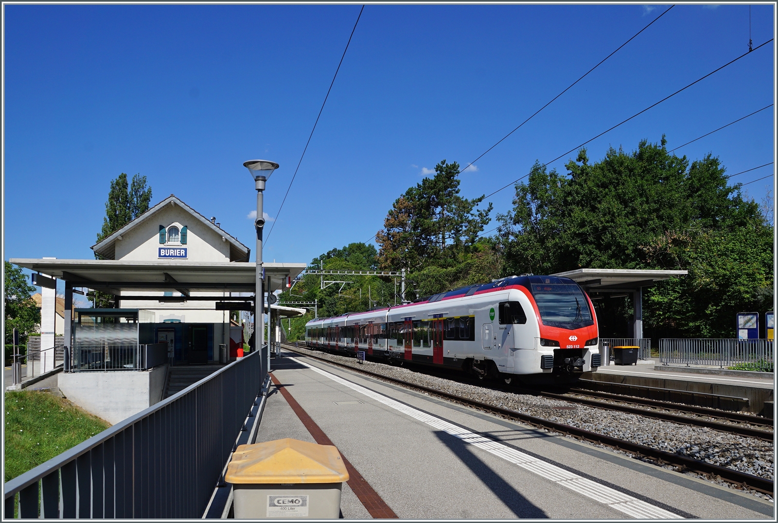 Während zei SBB Flirt3 RABe 523.1 auf Gleis 2 in Burier halten, zeigt sie links im Bild die wenige Überzeugende Normgestaltung kleinerer Station in Burier, welche die Sicht auf das Gebäude verhindert und ein Fremdkörper im Bild darstellt.

30. Juli 2022