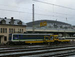 Im Schneeregen des Siegener Vorfrühlings stehen am 12.2.2020 diese Fahrzeuge genau gegenüber der Bahnsteige am Hauptbahnhof: Ein Gleiskraftwagen Typ SKL der KAF Falkenhahn, dahiner die 155