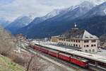 Vor dem stattlichen Empfangsgebäude von Scuol-Tarasp wartet die Ge 4/4 614 II  Schiers  vor einem Zug nach Disentis-Muster am 02.04.2022 auf die Abfahrt